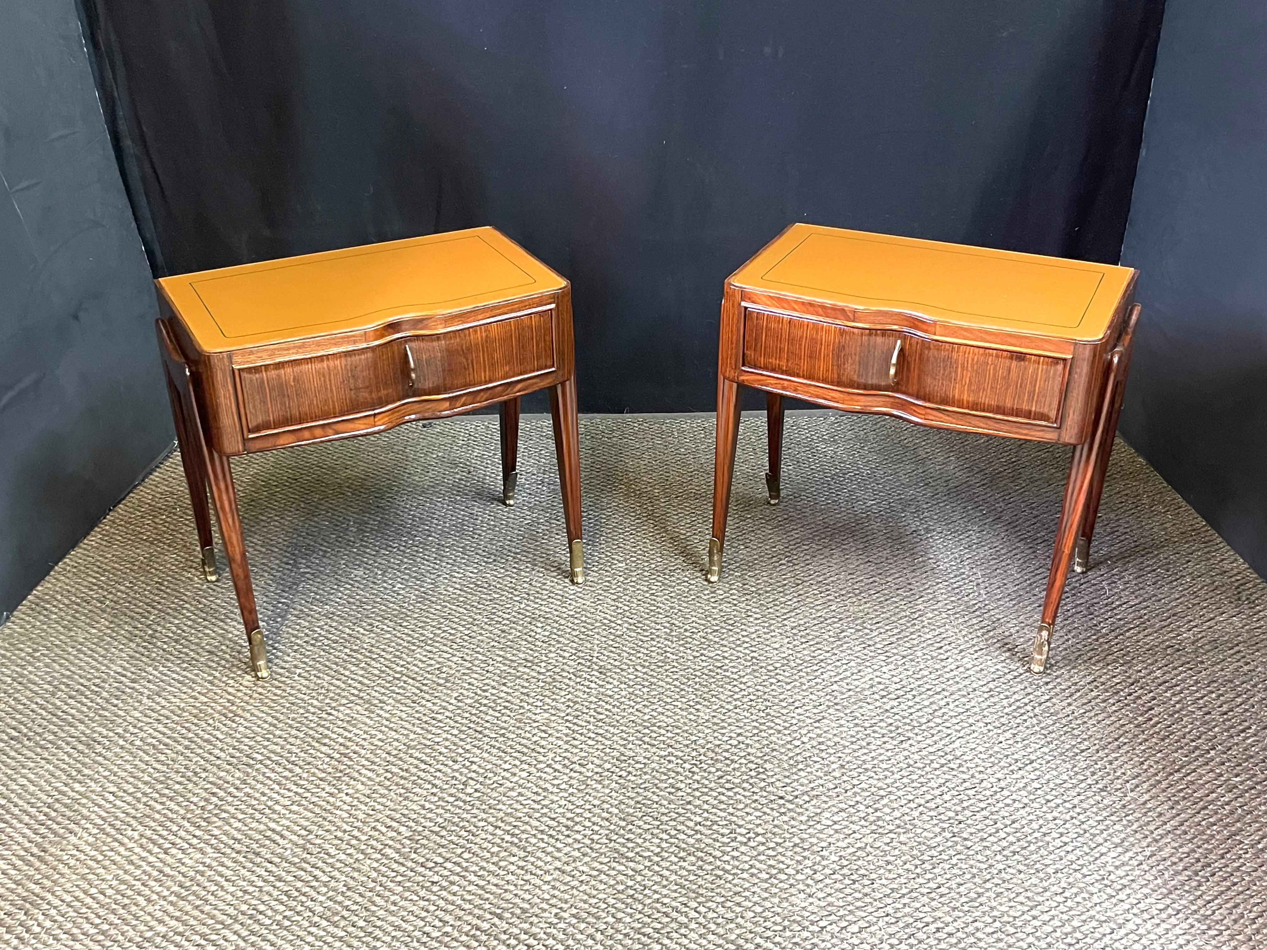 An elegant pair of Italian Mid-Century Modern bedside tables or nightstands in an original design by Vittorio Dassi. An artisan-made glass inset panel decorates each top in a neutral flesh tone with dark green trim. The shaped case is composed of an