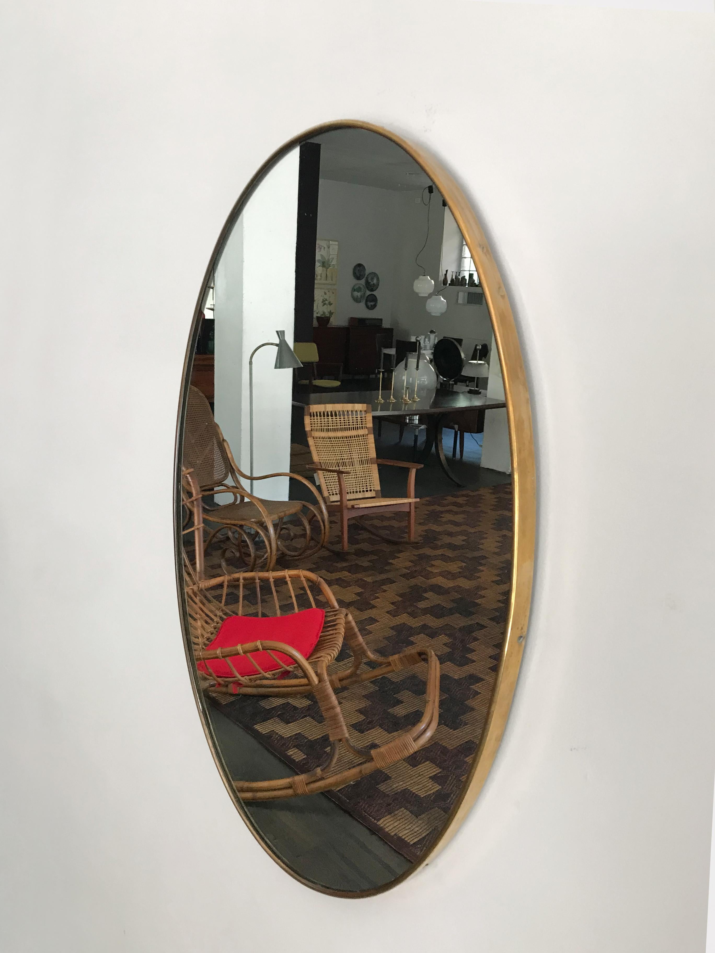 Italian Mid-Century Modern design oval wall mirror with brass frame, 1950s.
Please note that the mirror is original of the period and this shows normal signs of age and use.