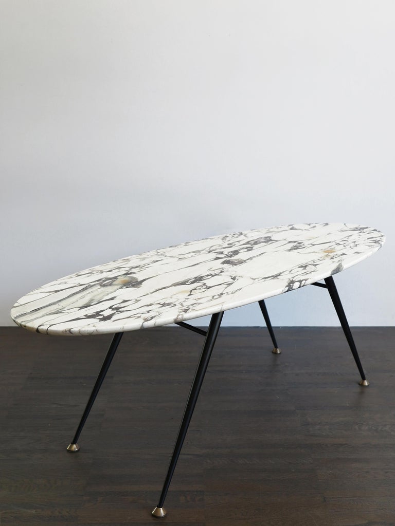 Italian Mid-Century Modern design oval marble coffe table, metal laquered structure and brass terminals, circa 1950s.

Please note that the item is original of the period and this shows normal signs of age and use.