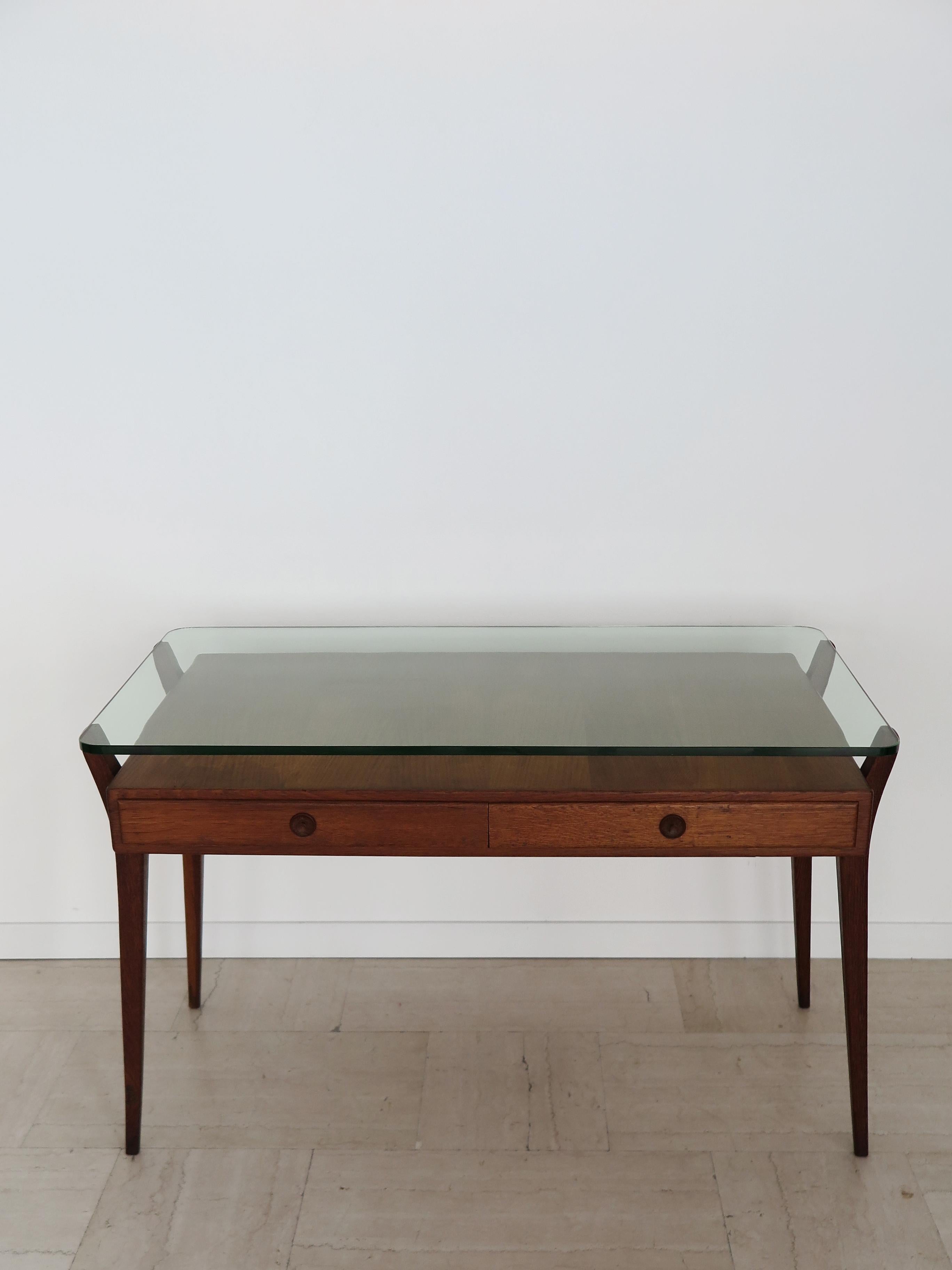 Escritorio italiano de diseño moderno de mediados de siglo con armazón de madera con dos cajones sobre los que descansa la gruesa tapa de cristal perfilada con esquinas redondeadas, Italia años 50

Ten en cuenta que el escritorio es original de la