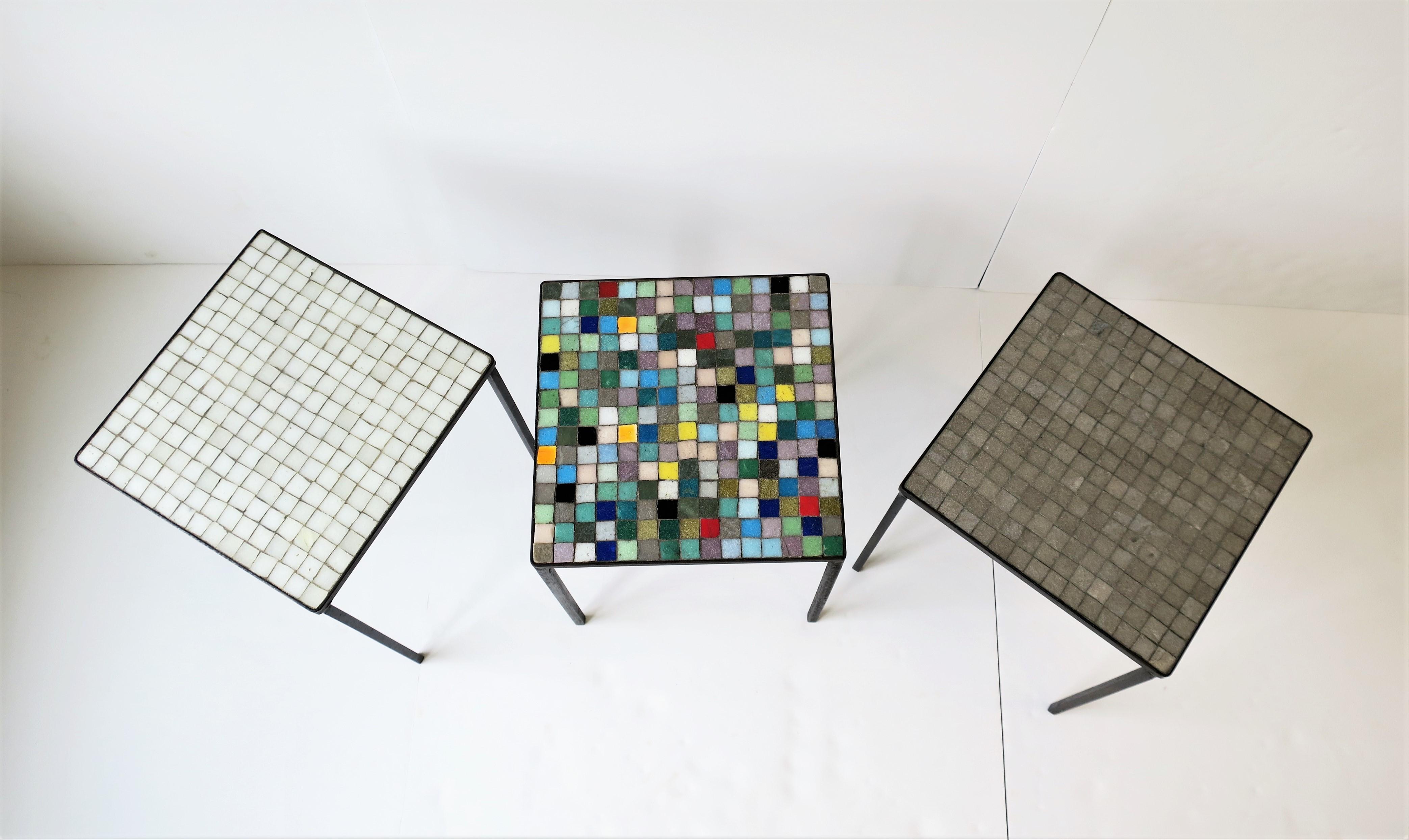 A beautiful set of three (3) Italian Mid-Century Modern small square white, gray/grey and multi-colored vitreous mosaic glass tile top stacking, side or drinks tables, circa mid-20th century, Italy. Tables have wrought iron frames with vitreous tile