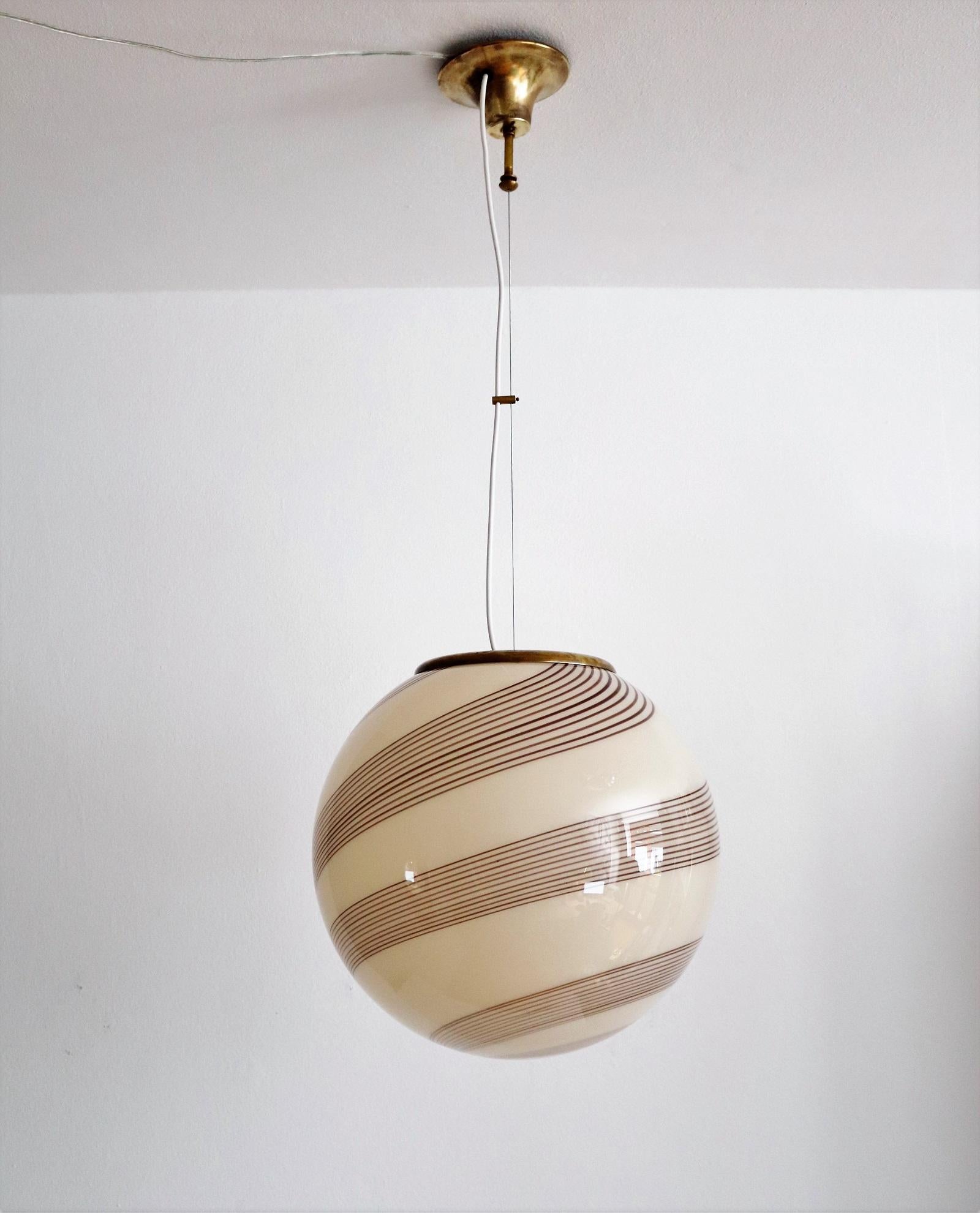 Beautiful and elegant Murano glass globe pendant lamp with brass details.
Made in Italy in the 1960s.
The elegant Murano glass has a soft light yellow-brown /amber color with darker brown stripes and is in original excellent condition without