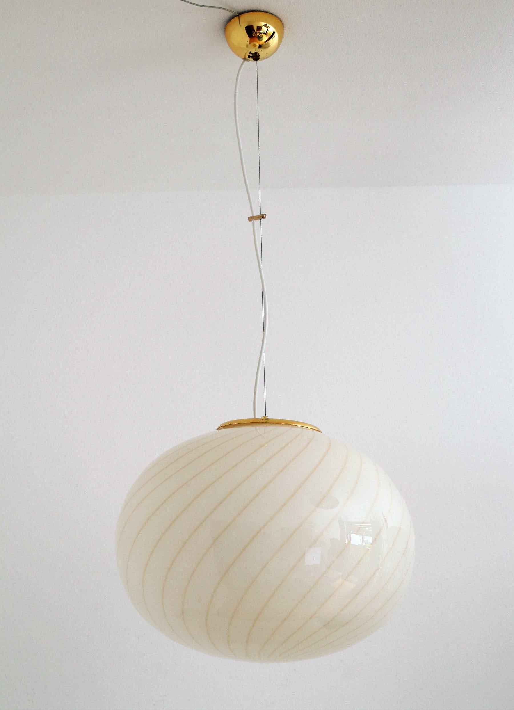 Beautiful and elegant Murano glass globe pendant lamp in cream - amber color with brass details.
Made in Italy in the 1970s.
Fine stripes in amber-yellow color are worked into the cream Murano glass. The glass globe is entirely hand-craftet.
The