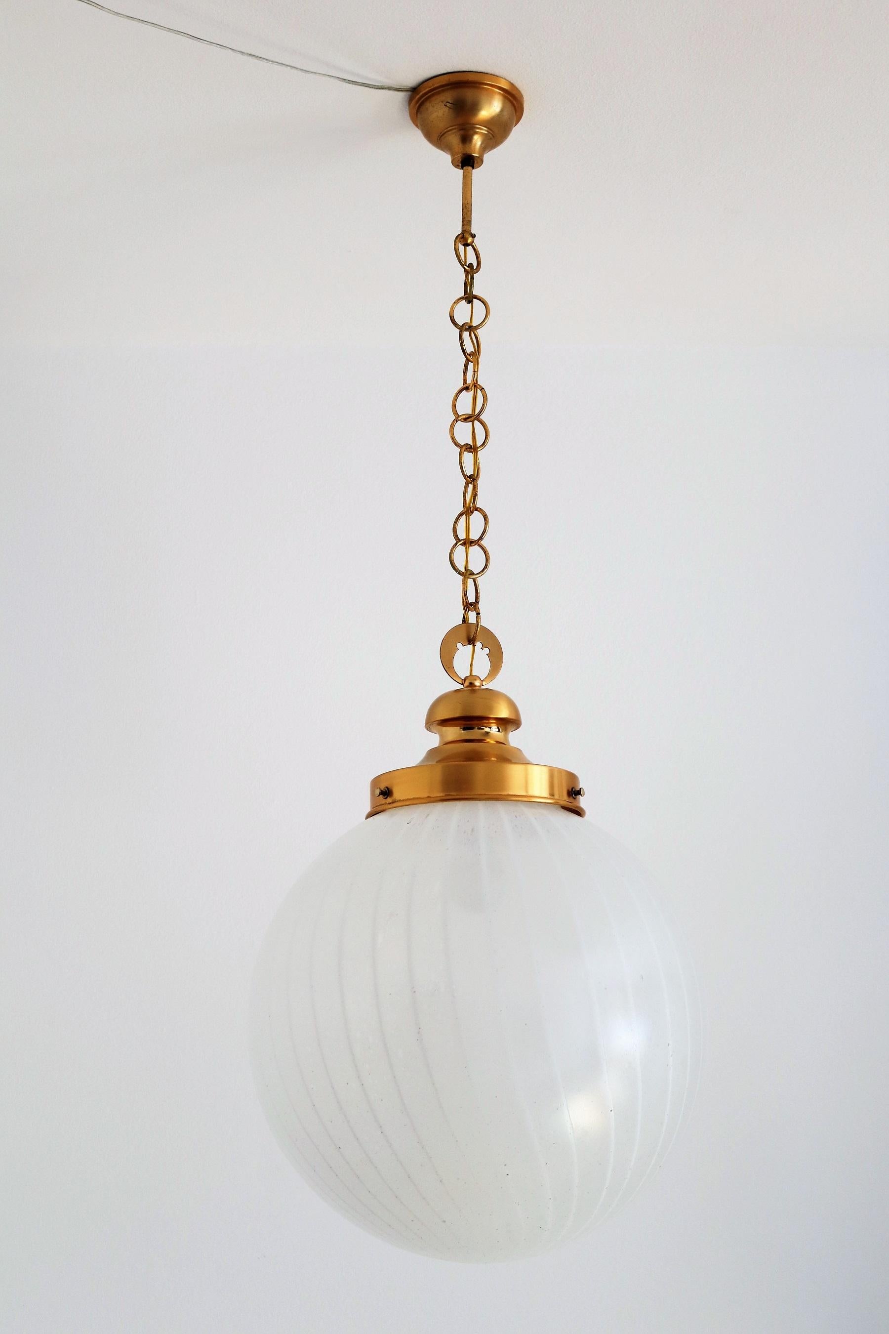 Schöne und große elegante Murano Glas Kugel Pendelleuchte mit starken Messing, Gold Metall Details. Hergestellt in Italien von Lampter in den 1960er Jahren.
Das Murano-Glas in schneeweißer Farbe mit weißem, dünnem Wirbel hat unzählige kleine Blasen