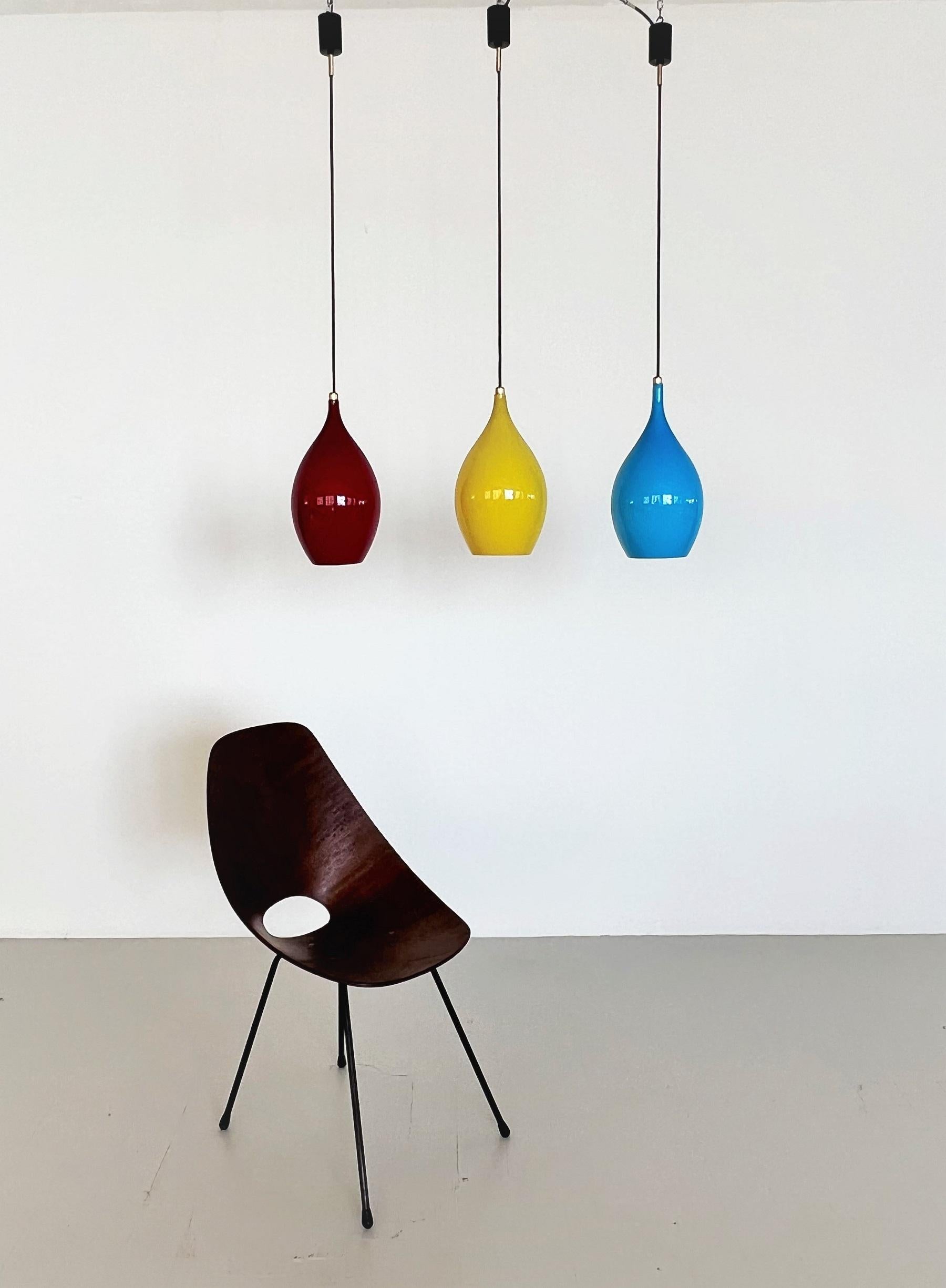 Beautiful pair of three glass pendant lights in different, shiny colors: red, blue and yellow.
Made in Murano, Italy in the midcentury of the 1960s - 1970s, typically in the style of Vistosi. 
All three lamps are in great shape and condition, and