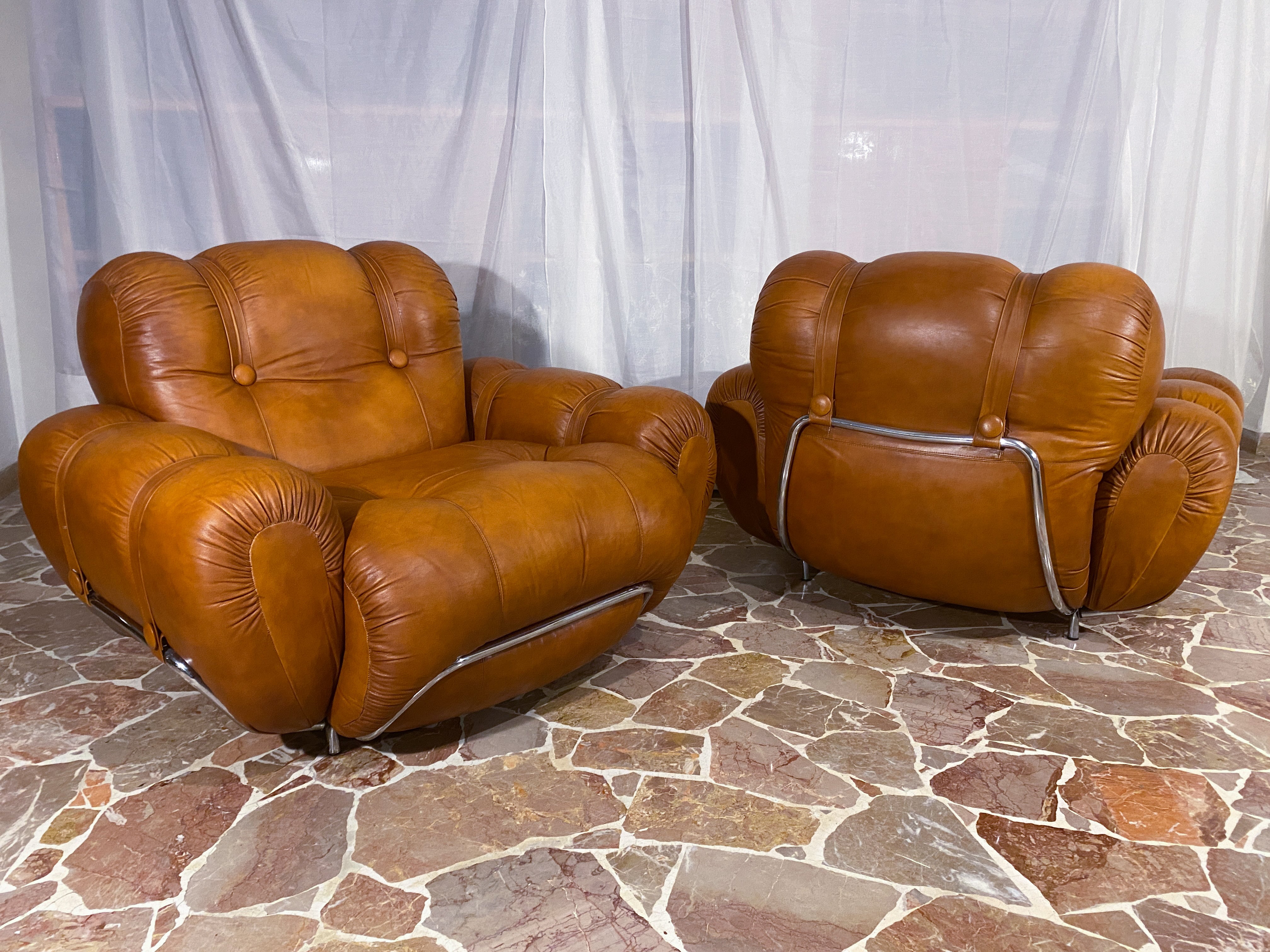 A stunning pair of armchairs made in Italy in the 1970s. The seat is very comfortable and supportive. The pads are still original and in very good condition. Original natural leather upholstery in very good condition from the period, a skilled