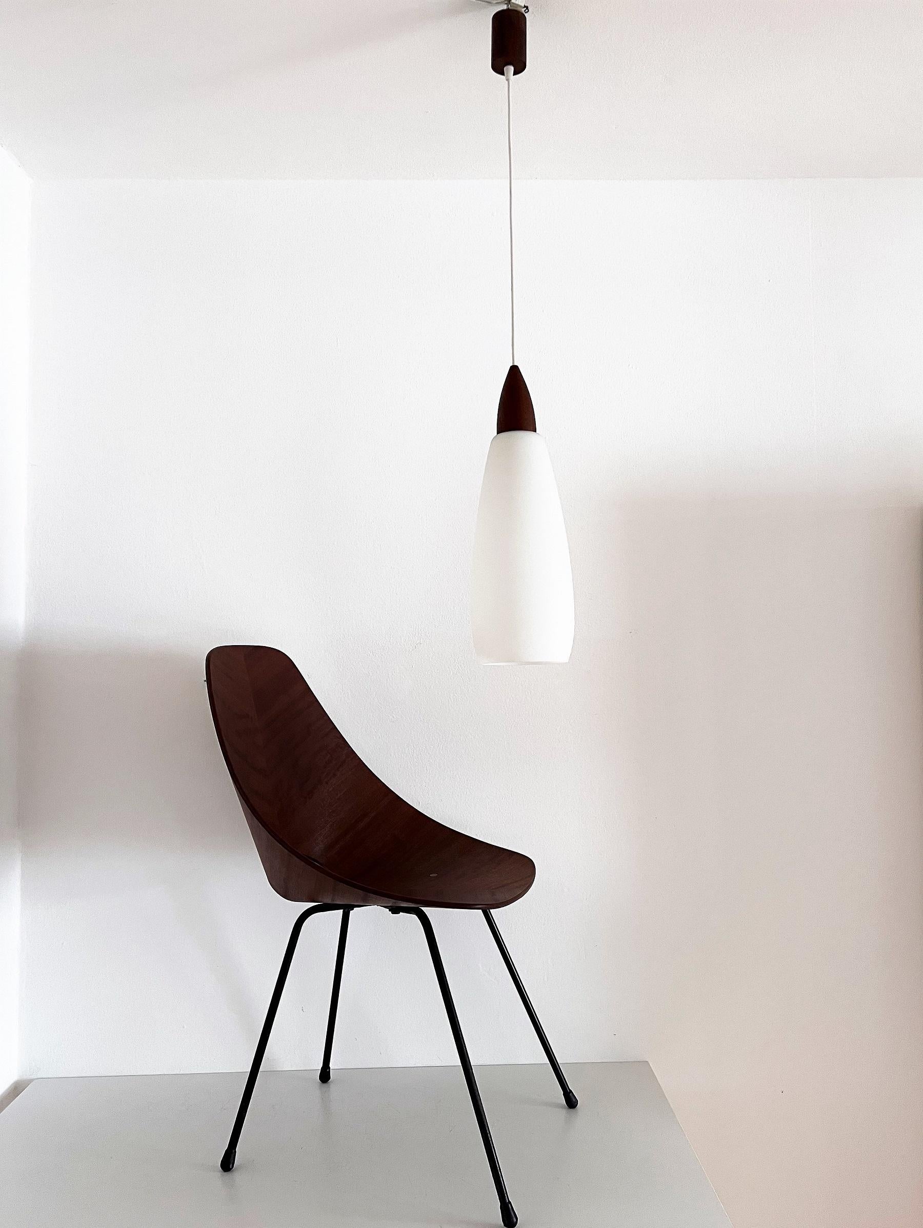 Beautiful glass and teak wood pendant lamp from the mid-century.
Made in Italy in the 1960s.
Fine craftsmanship on the teak wood parts, as well as the hand-crafted milk glass with soft touch.
Amazing soft light when illuminated.
The total height