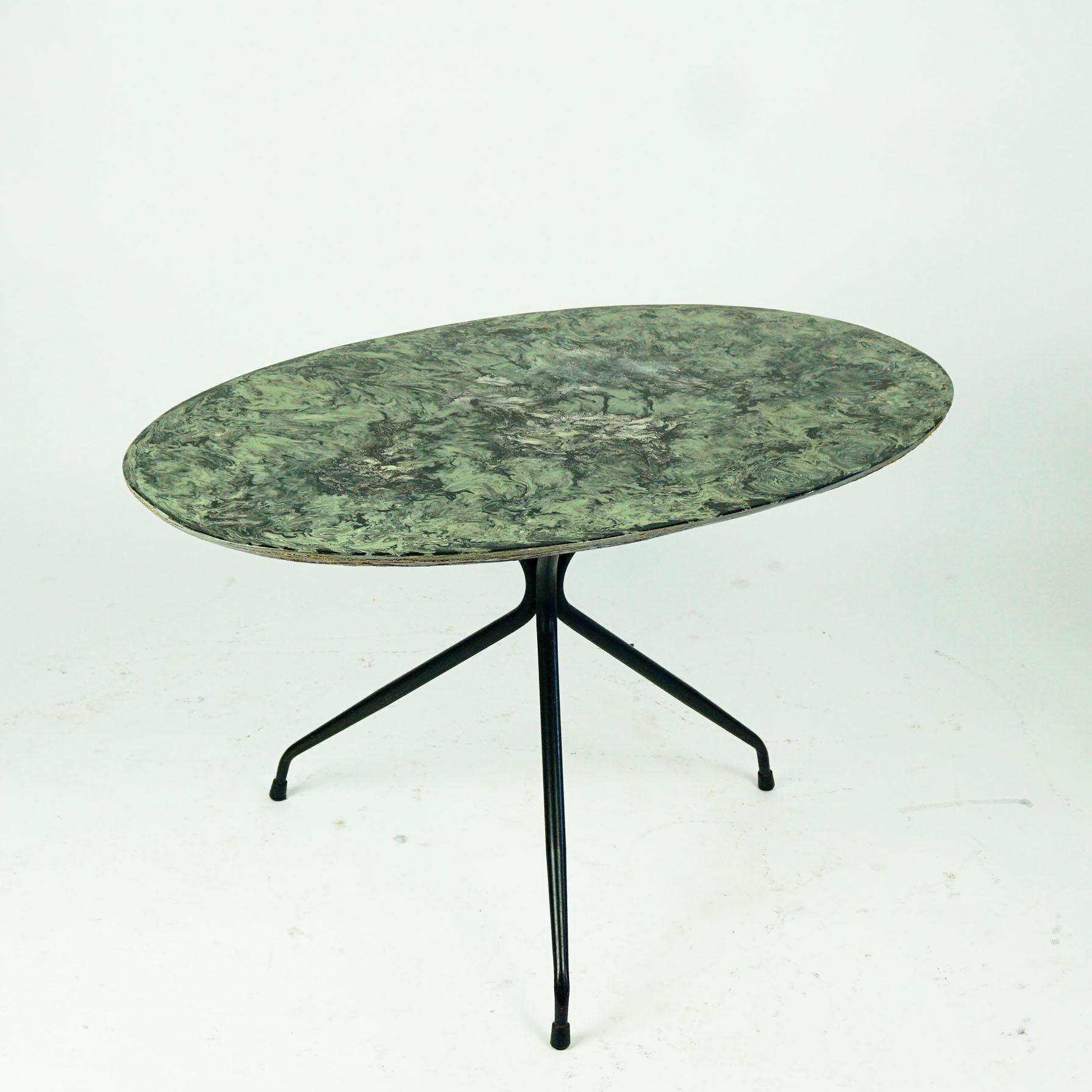 This charming small midcentury coffee or cocktail table has been designed and manufactured in italy 1950s.
It features a black lacquered metal tripod base with an oval faux marble top made of wood. Very elegant proportions, rubber shoes at the end