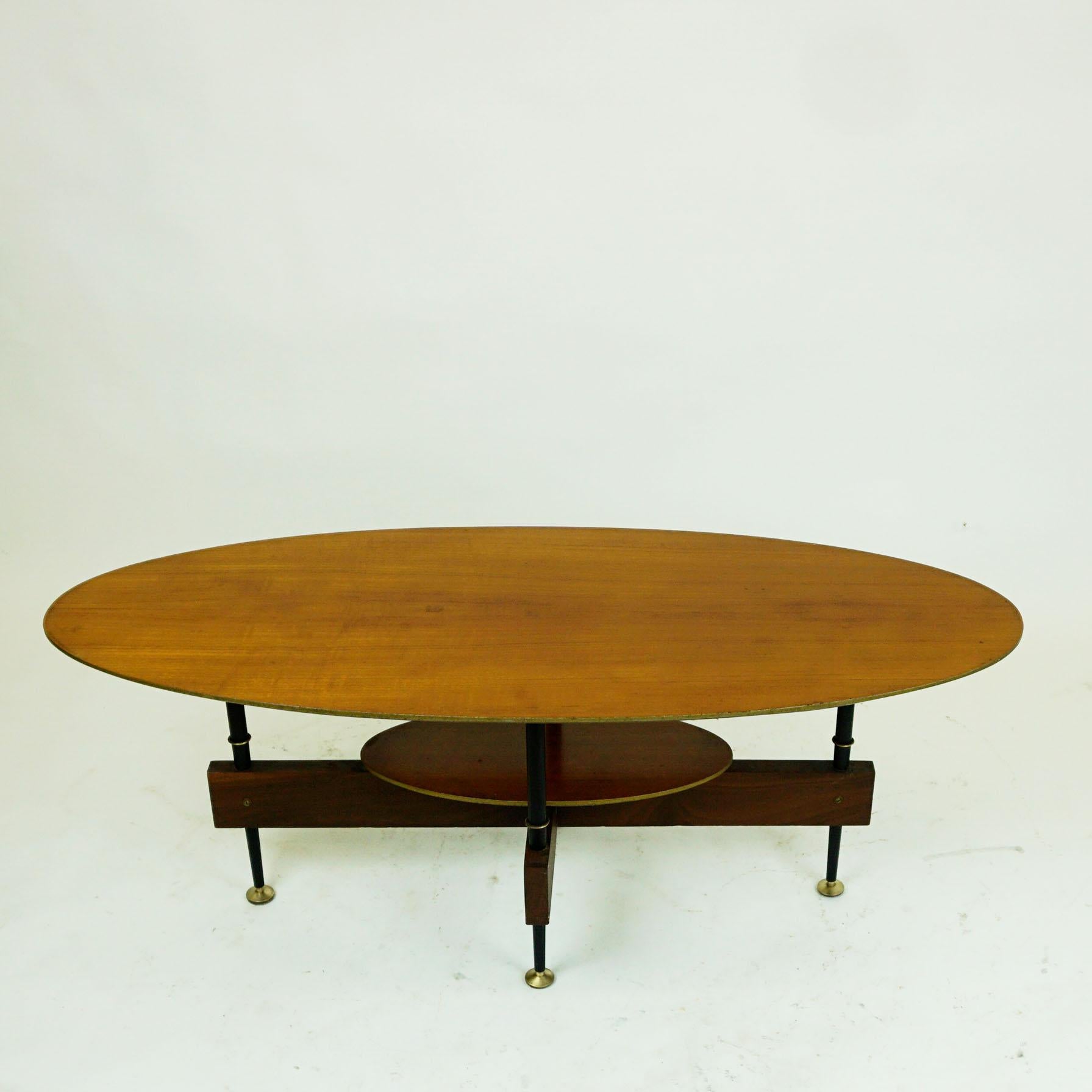 Small elegant Italian midcentury teak cocktail or coffee table designed in the 1950s. It features a oval teak wood top and black lacquered metal legs with brass details.
  