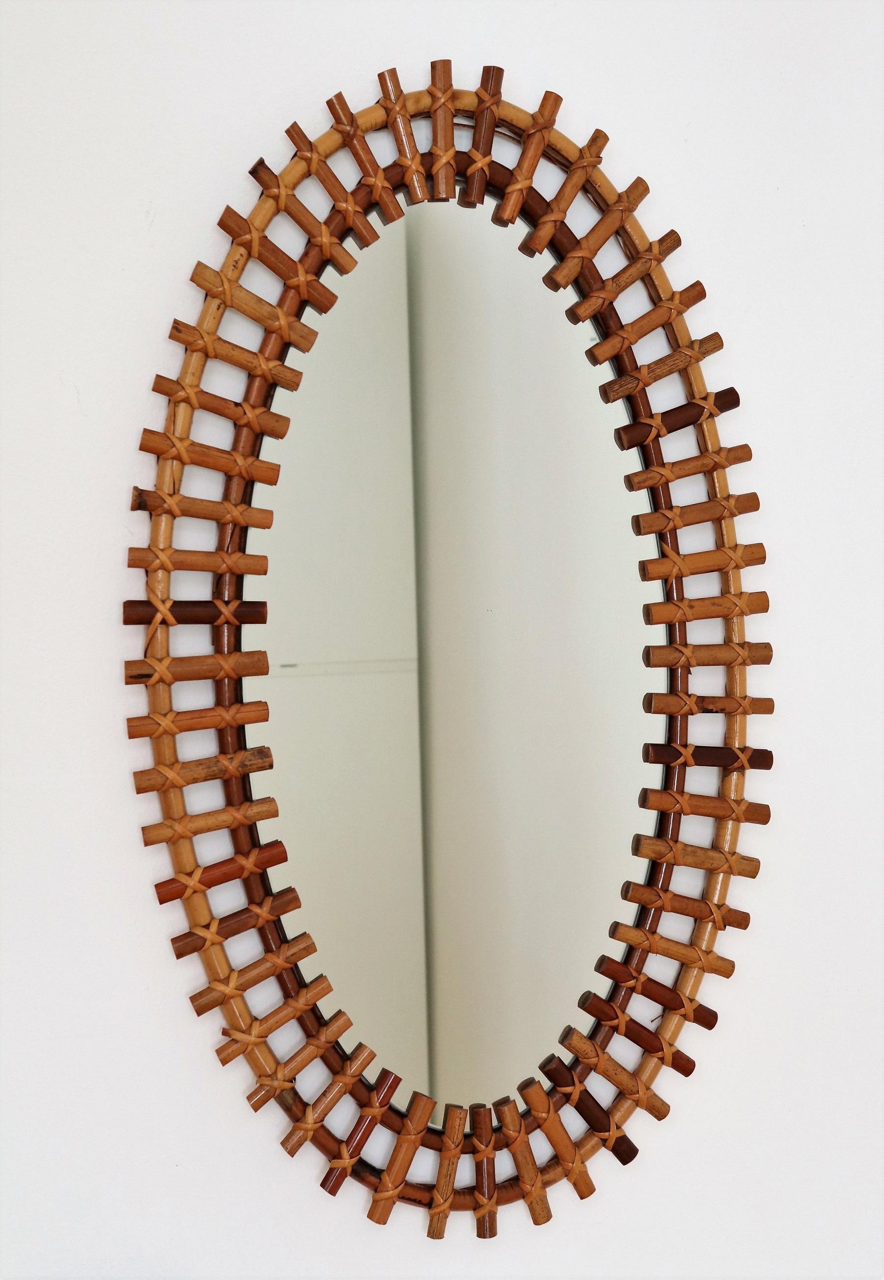 Beautiful Italian organic wall mirror which features a big oval frame made of bamboo reeds with contrasting hand-tied caning reed.
The mirror is made in Italy typically for the 1960s.
The mirror glass is in very good condition, as well as the