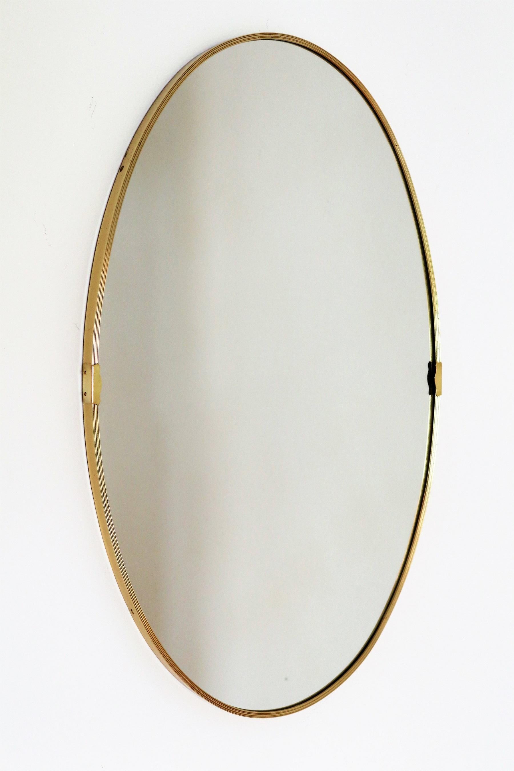 Beautiful Italian mid-century wall mirror with original frame made of golden aluminium and two brass details at both sides.
Made in Italy in the 1960s.
The wall mirror is in cleaned condition. 
The mirror glass has been renewed, and is therefore