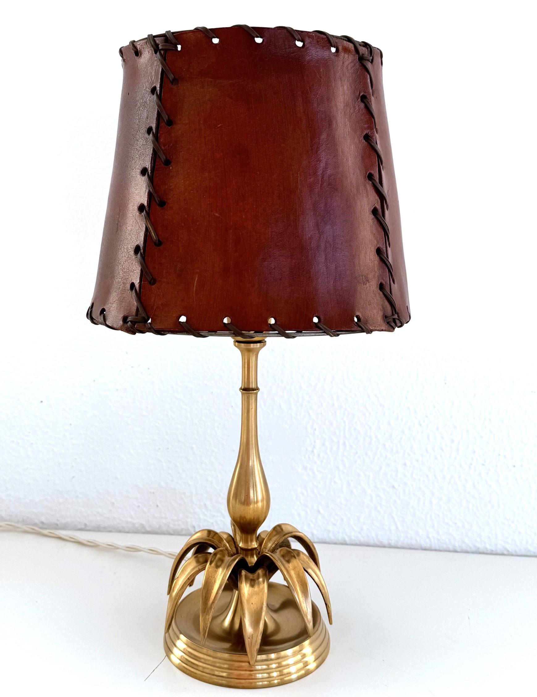 Petite lampe de table insolite et chic, fabriquée en Italie dans les années 70.
La base de la lampe est en laiton massif et comporte un anneau de feuilles de laiton recourbées vers le bas sur la face inférieure. 
L'abat-jour est constitué d'épais