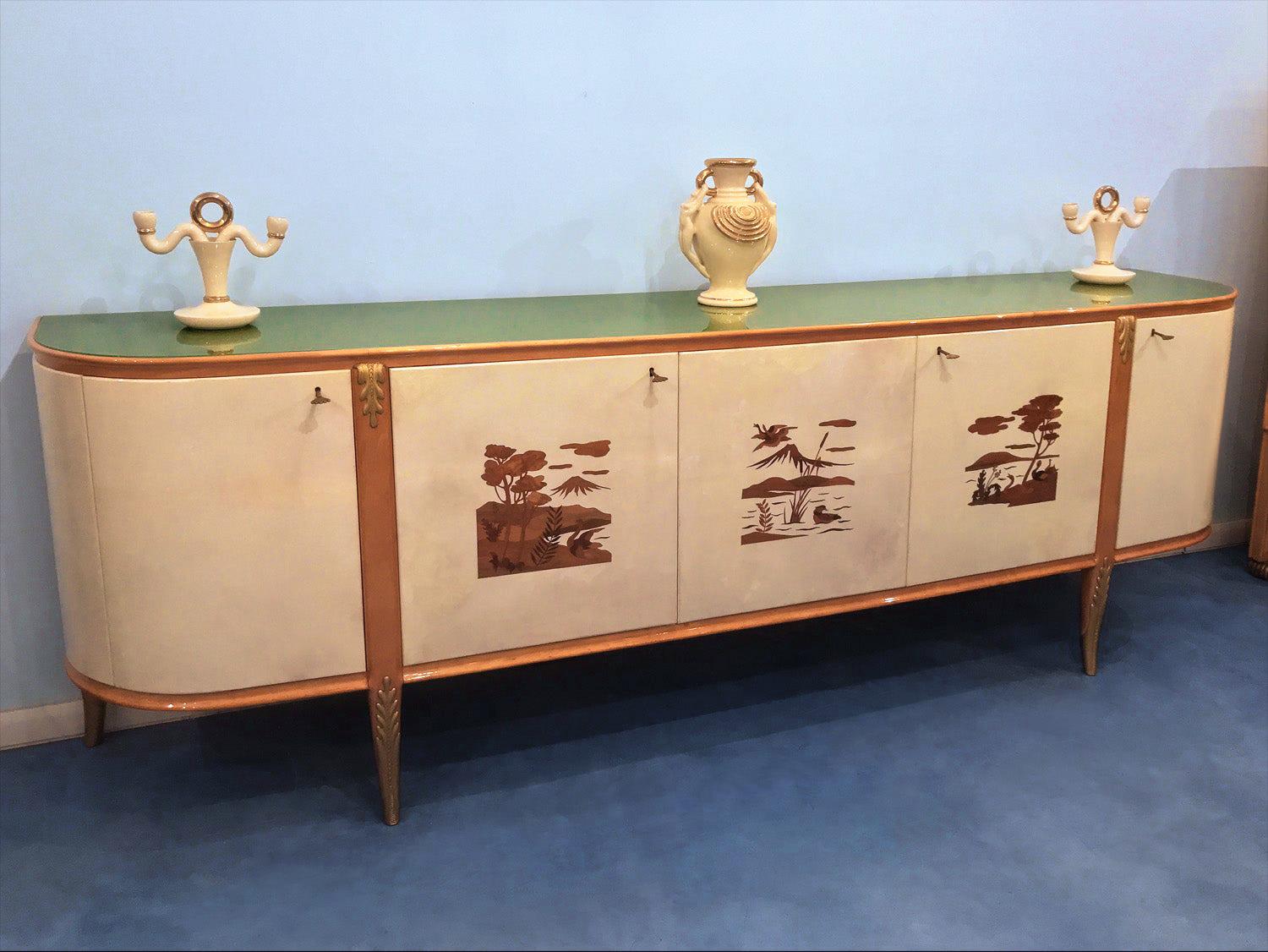 Very rare and fine sideboard designed by Giovanni Gariboldi in the late 1940s, possibly produced by Quarti.
The structure is in pearwood with carved giltwood and doors in parchment, decorated with superb scenes of landscapes inlaid.
Its glass