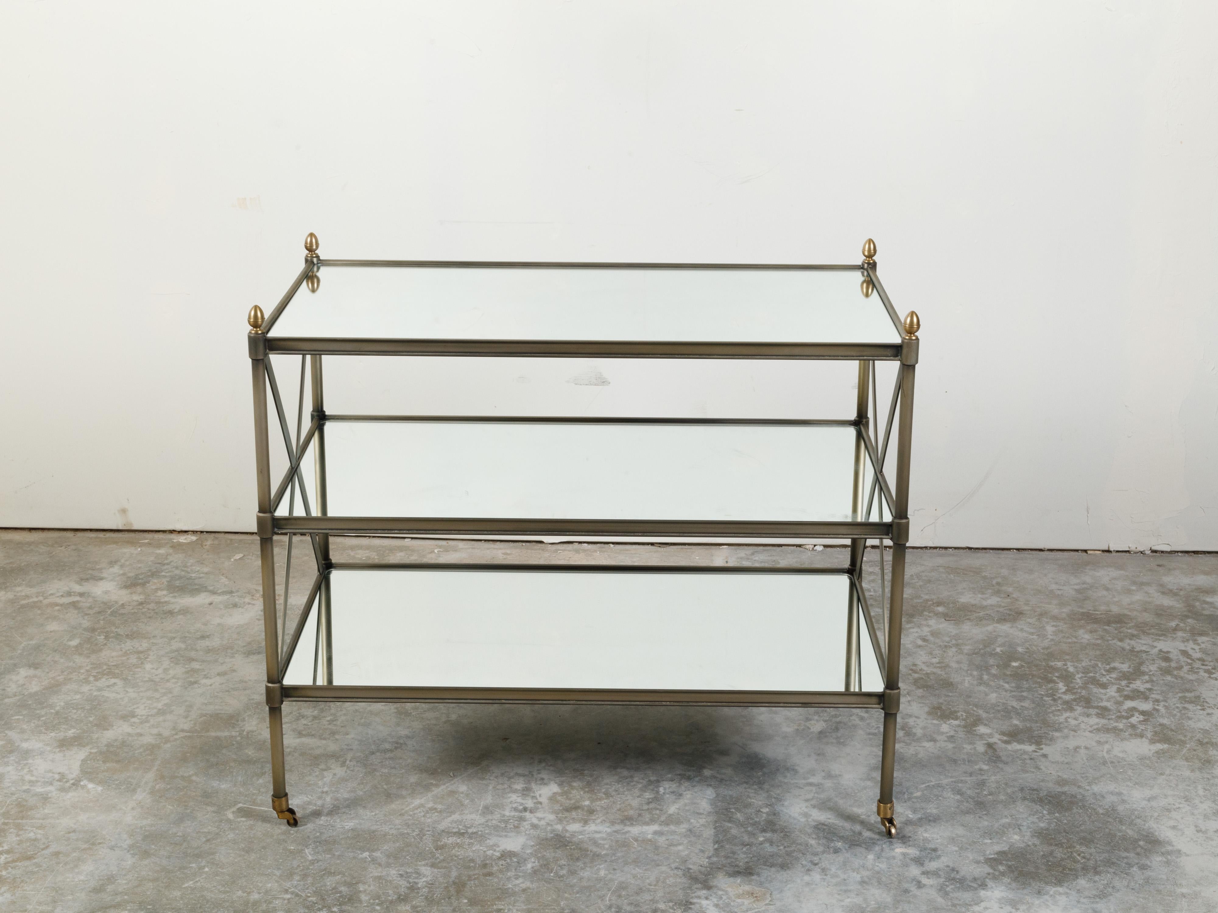 An Italian vintage trolley from the mid 20th century, with patinated metal, mirrored shelves and casters. Created in Italy during the midcentury period, this trolley features a rectangular mirrored top accented with petite brass acorn finials in the