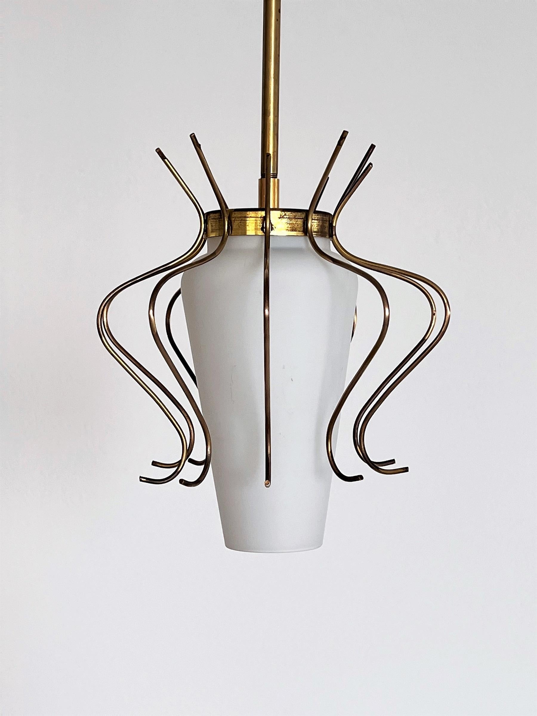 A wonderful and delicate ceiling lamp, made in the 50s in Italy.
The central opaline white glass is held with a clamp inside the lamp.
Around the lamp are curly details made of brass.
The lamp holder as well as the rod to the ceiling and the