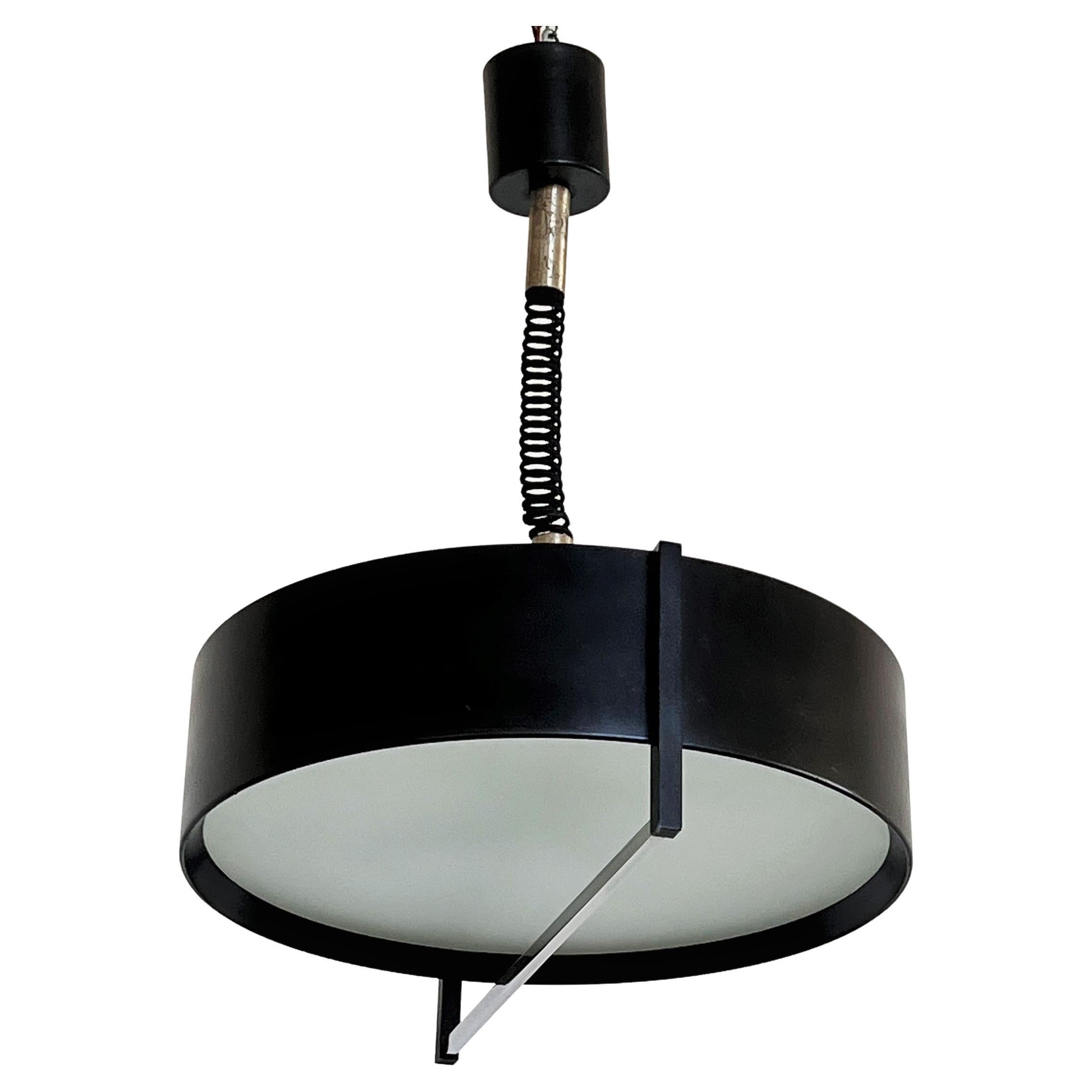 This rare Italian pendant lamp is in very good original vintage condition. Manufactured in the 1960s.
The body is black painted metal with normal vintage traces but no defects. The lower rod to adjust the lamp is made of chrome plated brass. 
The