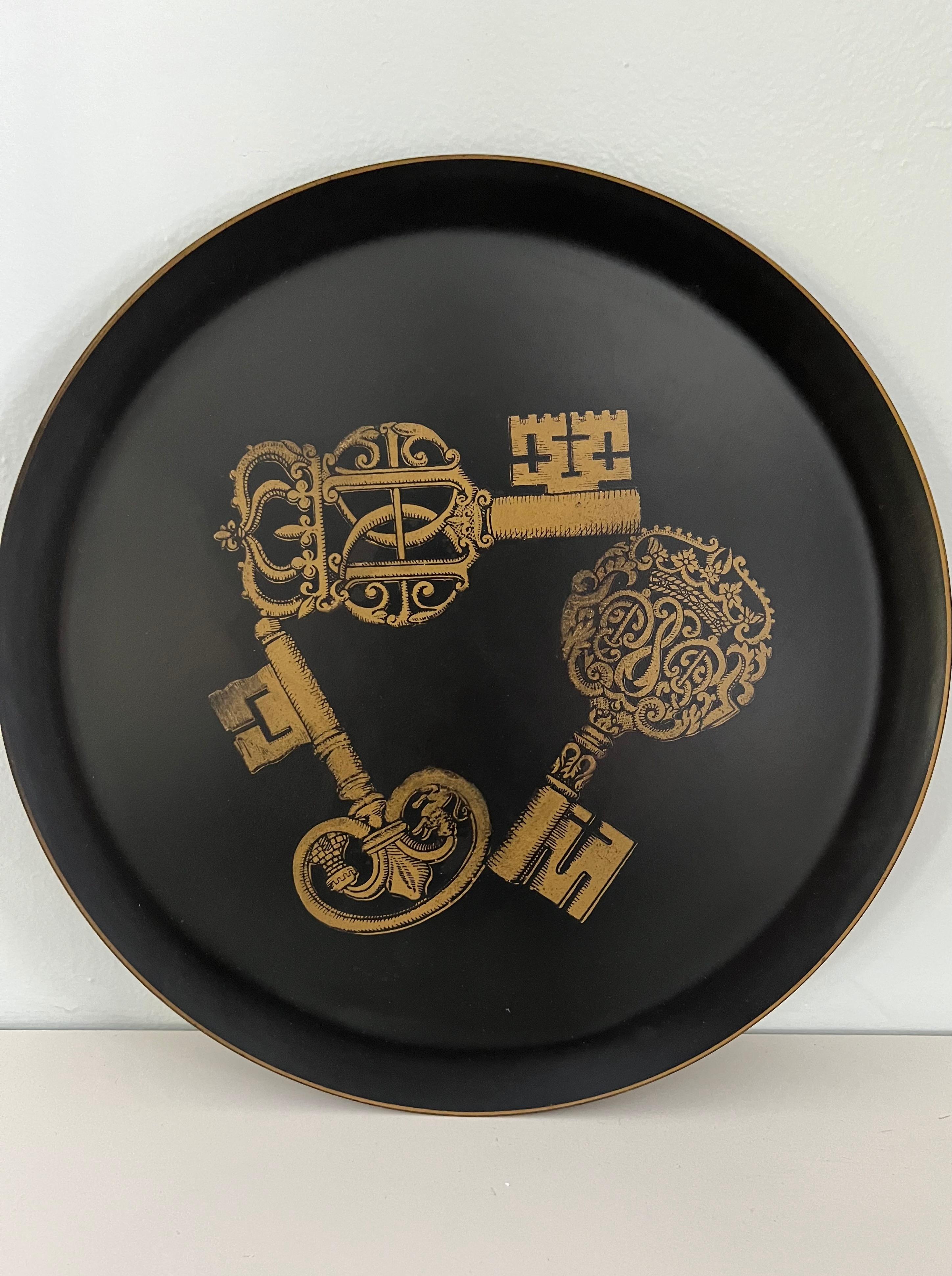 Matte black round tray featuring three gold ornamental keys by Piero Fornasetti.