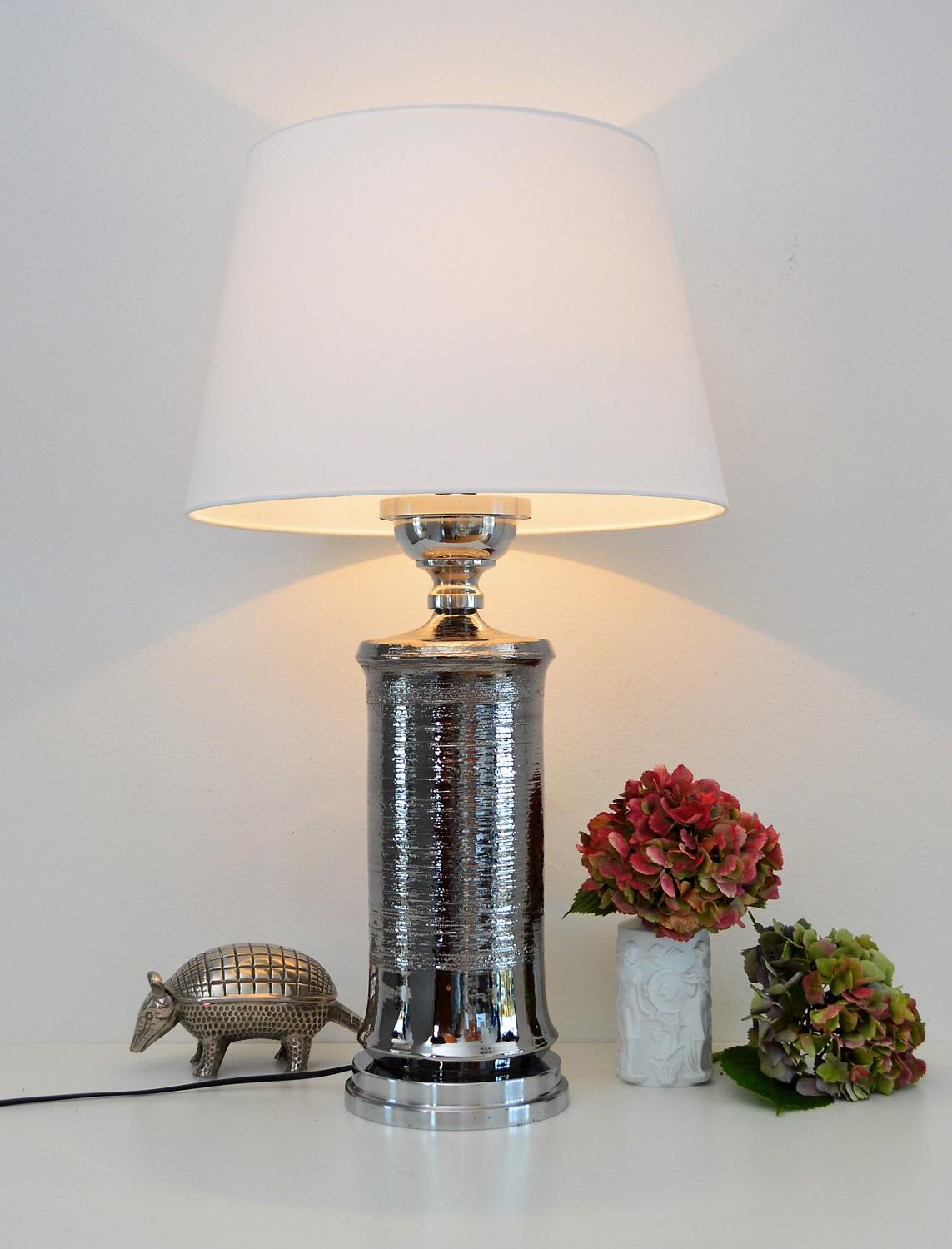 Beautiful ceramic table lamp made in the 1970s by Bitossi, Italy.
The middle ceramic part from Bitossi is with shiny silver glaze called platinum and in mint condition.
The lamps base and upper part is chrome plated metal; there is a cord too to