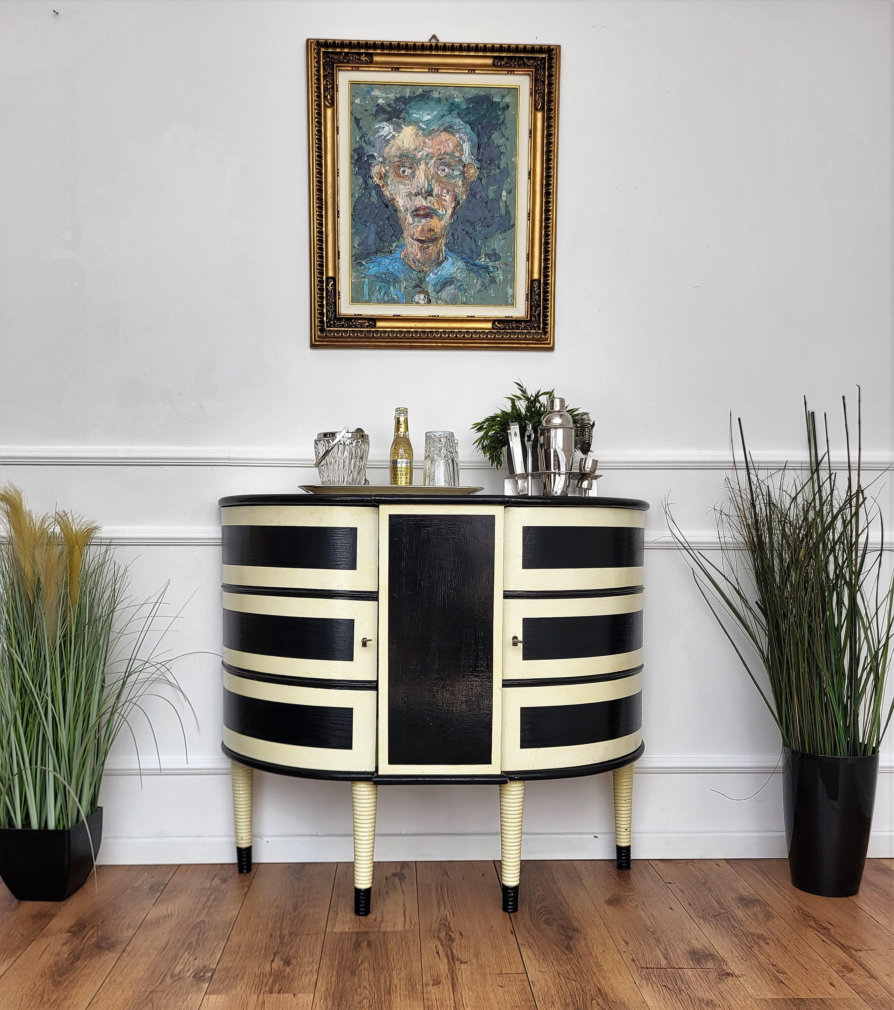Beautiful and elegant Italian dry bar cabinet in the typical design and shapes of Mid-Century Modern pieces, in walnut wood, painted in black and white with great decorative use of geometric motives on the front and two doors with an amazing