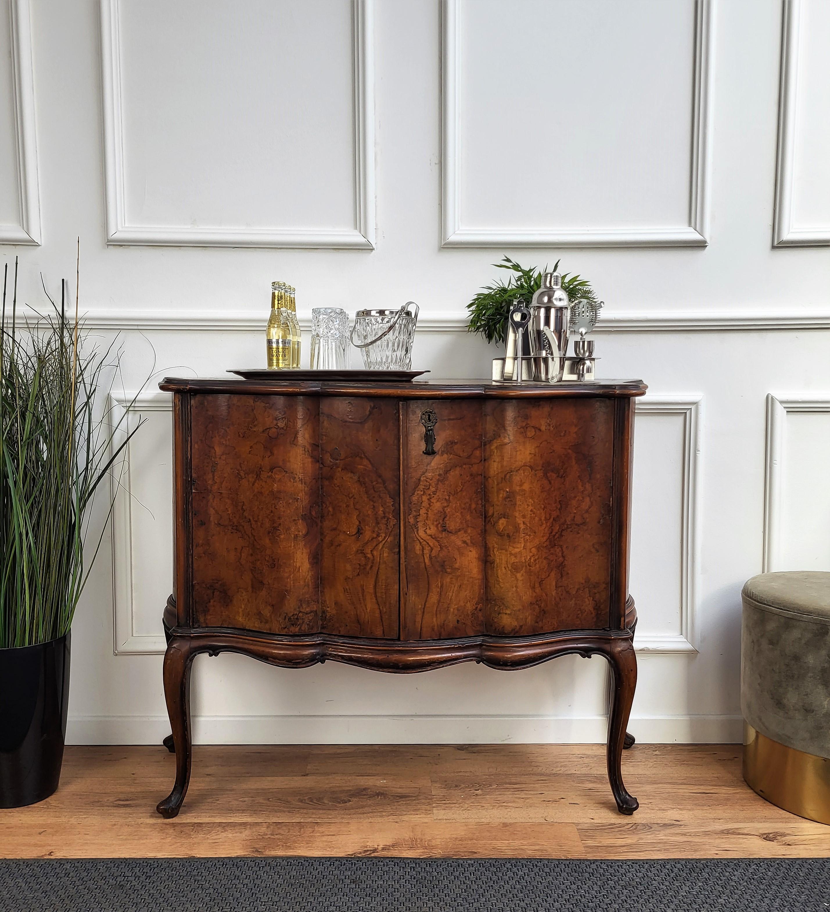 Beautiful and elegant Italian dry bar cabinet in the typical design and shapes of Mid-Century Modern pieces, in walnut and burl wood, with great decorative use of the veneer and geometric gilt motives on the two doors with an amazing interior part