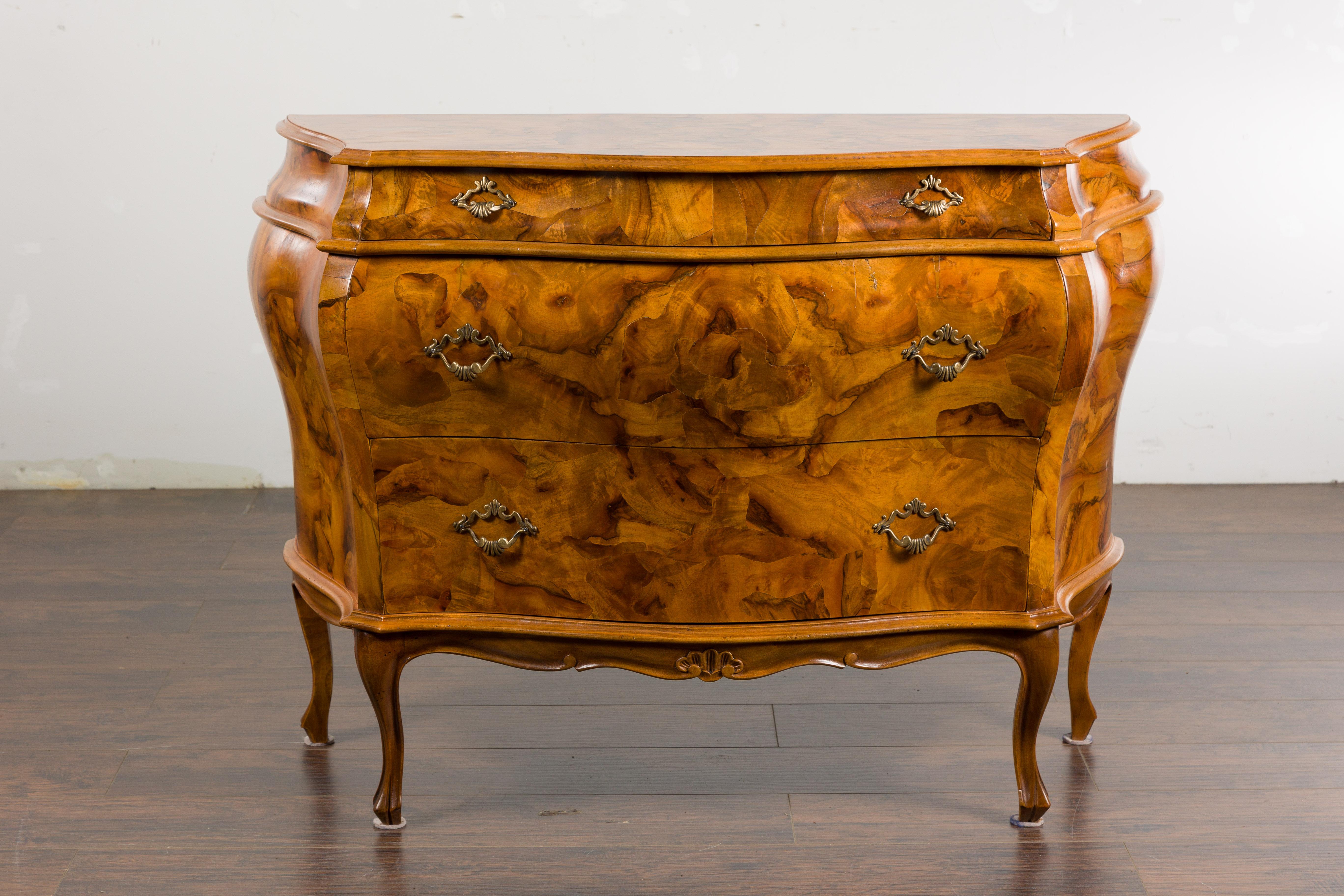 An Italian Rococo style walnut veneered bombé crossbow chest from the mid 20th century with serpentine front, three drawers, cabriole legs and exquisite veneer. Add a touch of elegance to your living space with this exquisite Italian Rococo style