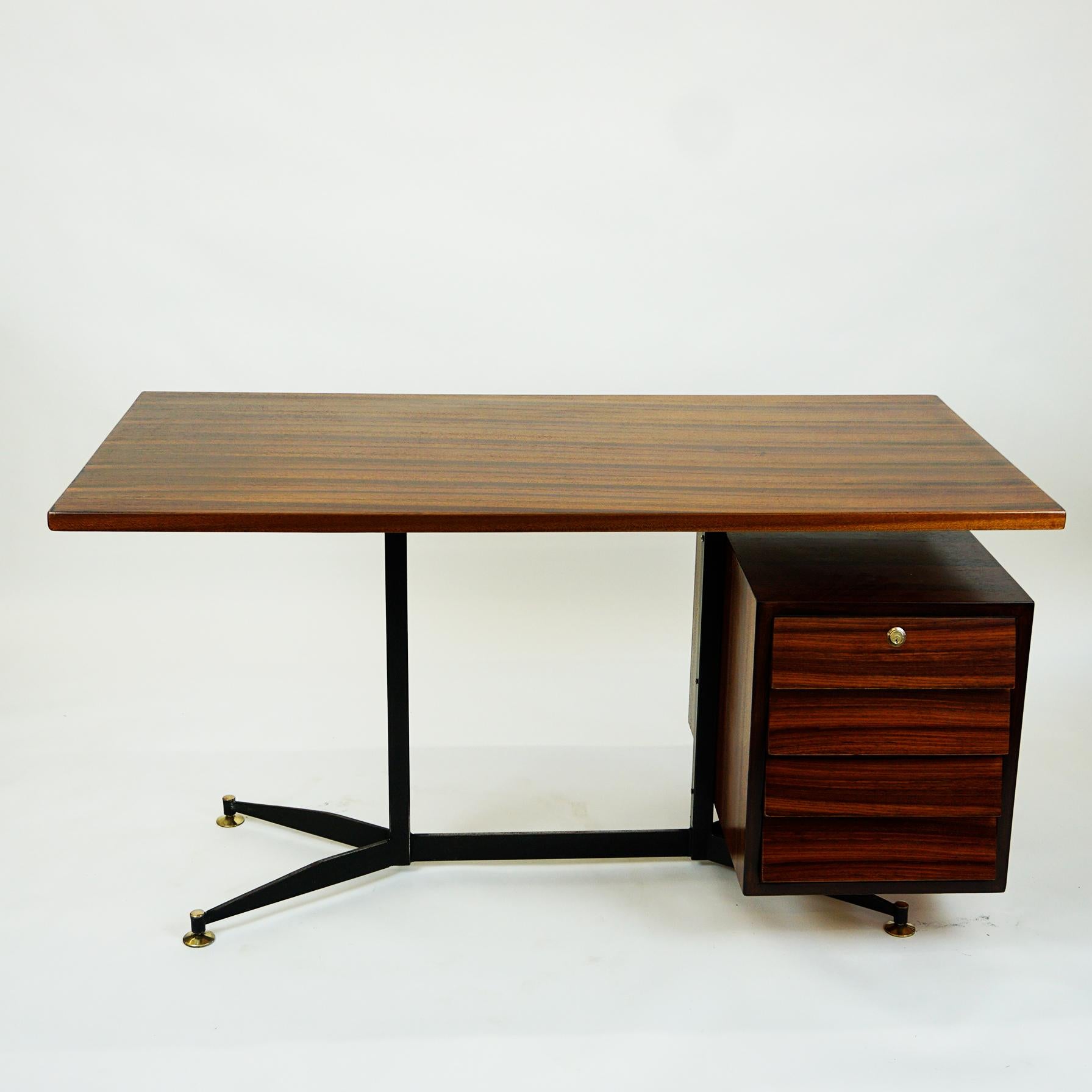 This Italian midcentury rosewood desk features steel construction with brass details, floating top design, and a storage unit on the right side with four drawers for plenty of storage. The Design of the steel base with the brass feet is very close