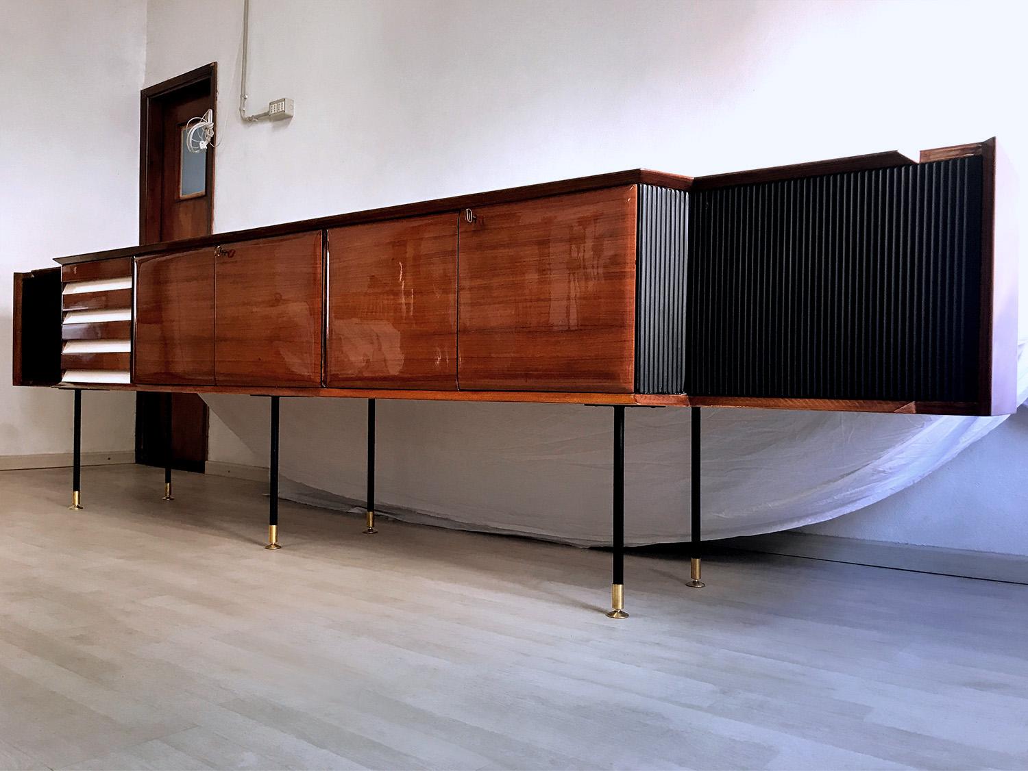Stunning and very rare rosewood long sideboard designed by Vittorio Dassi in the 1950s.
The structure is a unique piece composed by a long floating cabinet supported by metal legs finished with height-adjustable brass feet.
The doors hide large