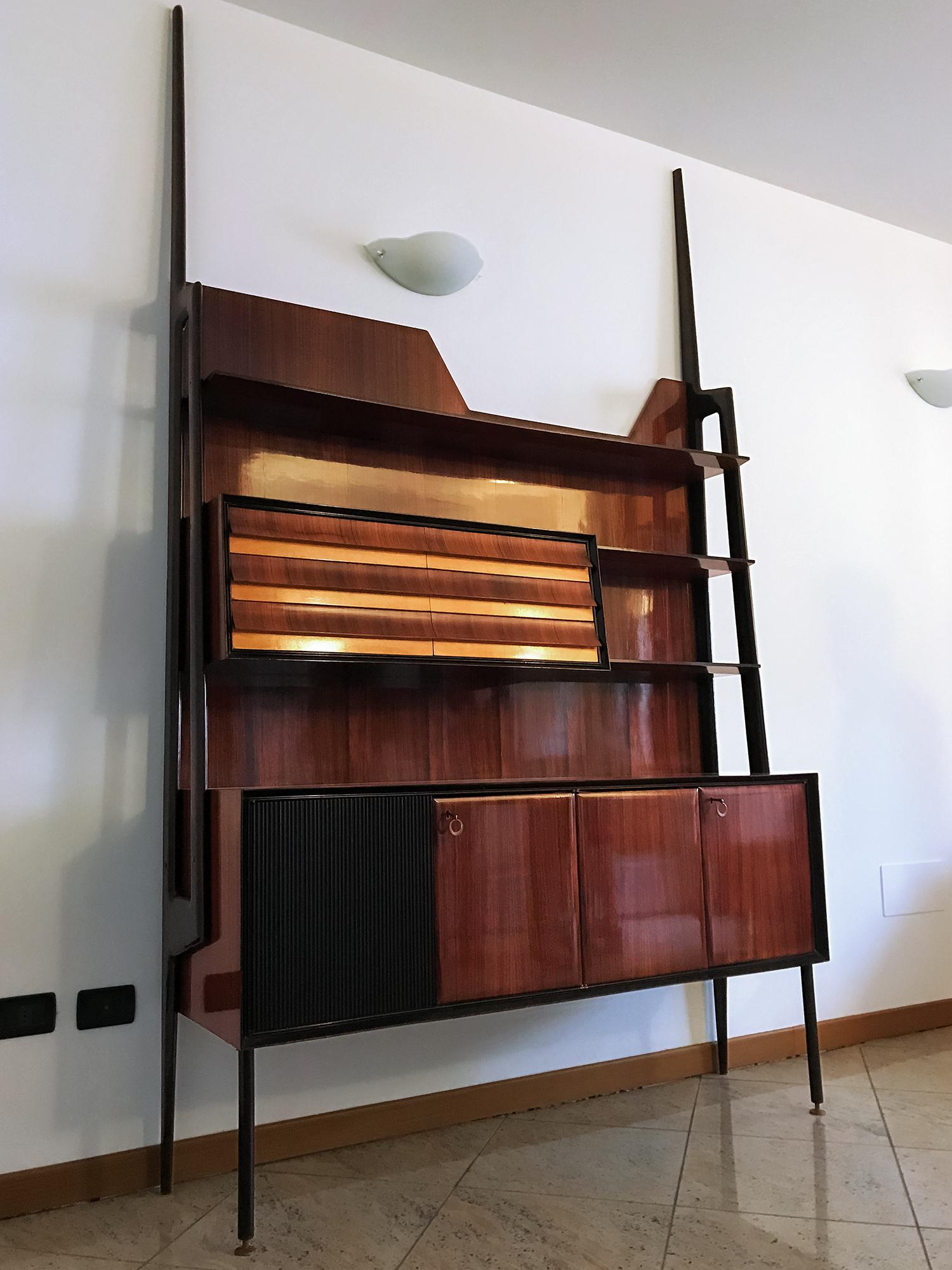 Stunning Italian self-standing bookcase designed by Vittorio Dassi in the 1950s.
The structure is of veneered rosewood, equipped with drawers, and supported by uprights with the form of long lances in ebony stained wood.
The item is in good