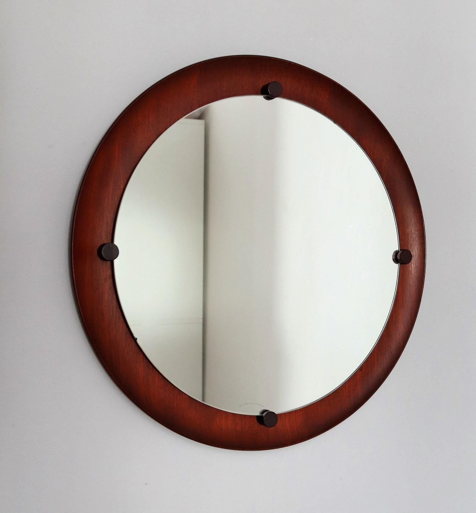 Beautiful round wall mirror made of a curved teak wood base with four wooden colored brackets, which hold the mirror in front of 50 cm (19.7in).
Made in Italy in the 1960s approx.
Backside a cord for wall hanging and a stamp of Italian Manufacturing