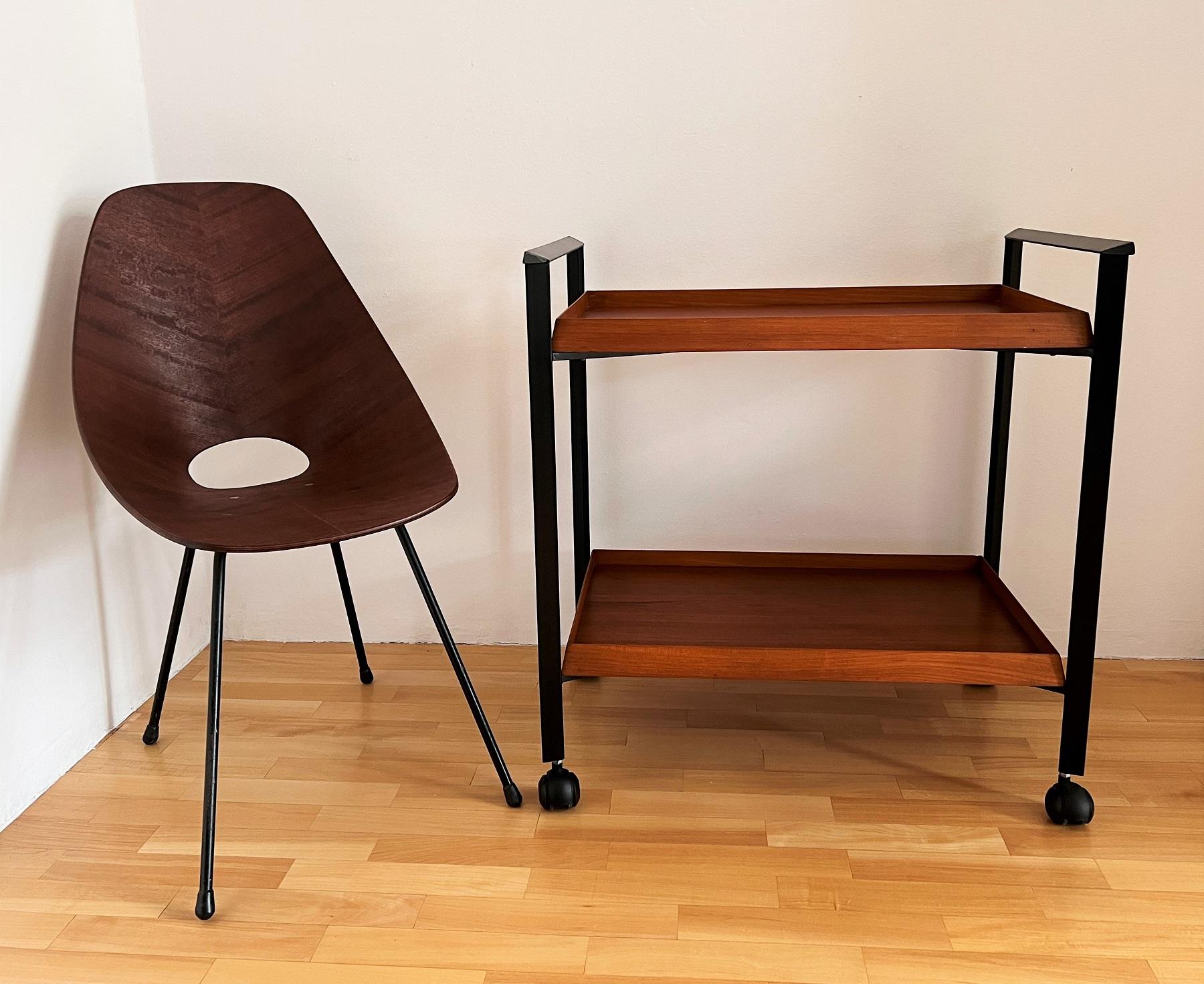Classic serving cart, bar or trolley from the Italian mid-century, 1970s of great quality.
The base of the trolley is made of black metal with two beautiful teak wood veneer shelves.
The particular shape and beauty of this cart is given by the cut