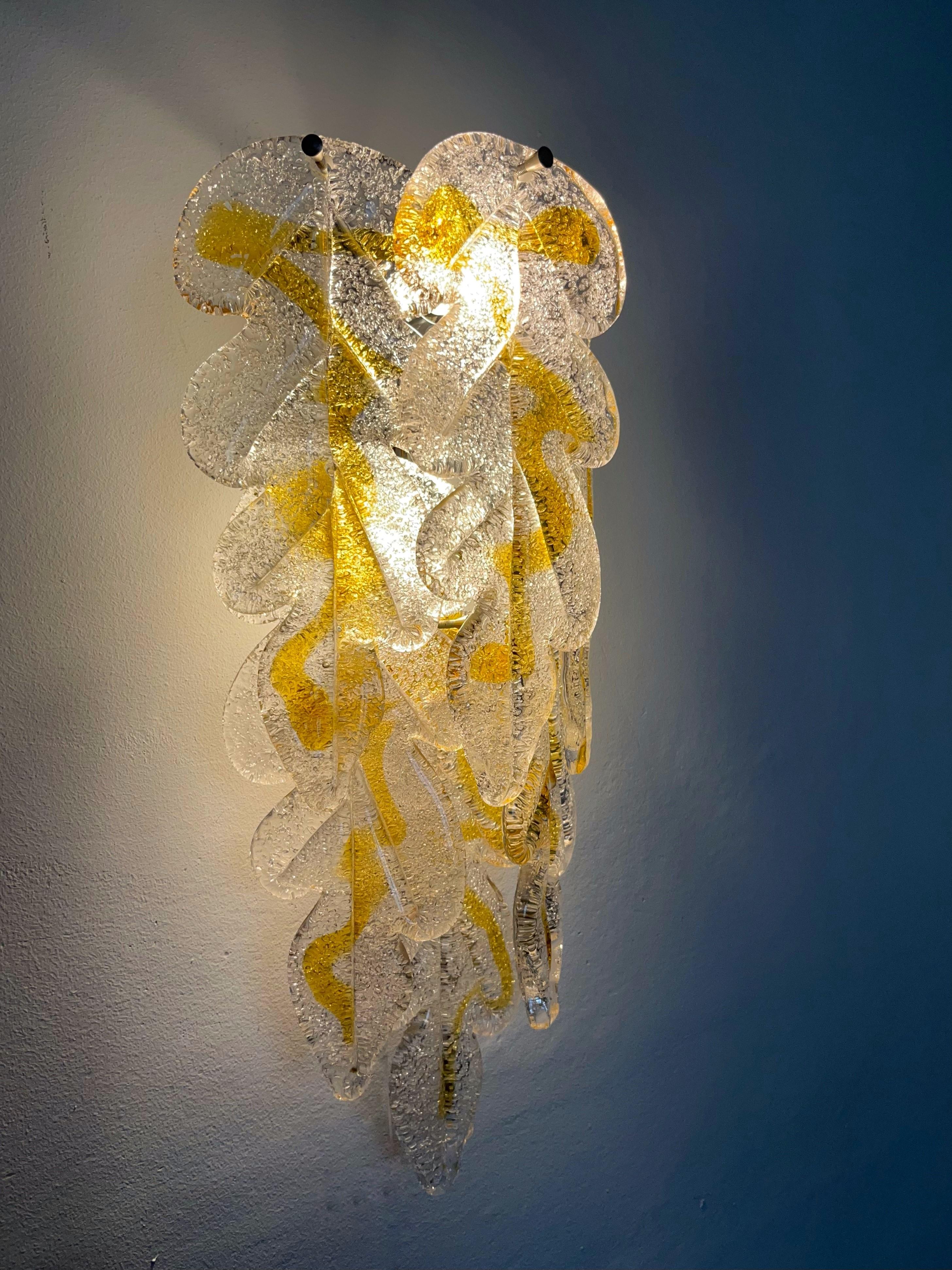 Marvelous, stunning and long Pair of Italian clear yellow amber Murano glass Wall Sconces from 1970s. These fixtures were designed and manufactured during the 1970s in Italy for the Venice Company “Mazzega”.
Each Wall Sconce is composed by 6 units