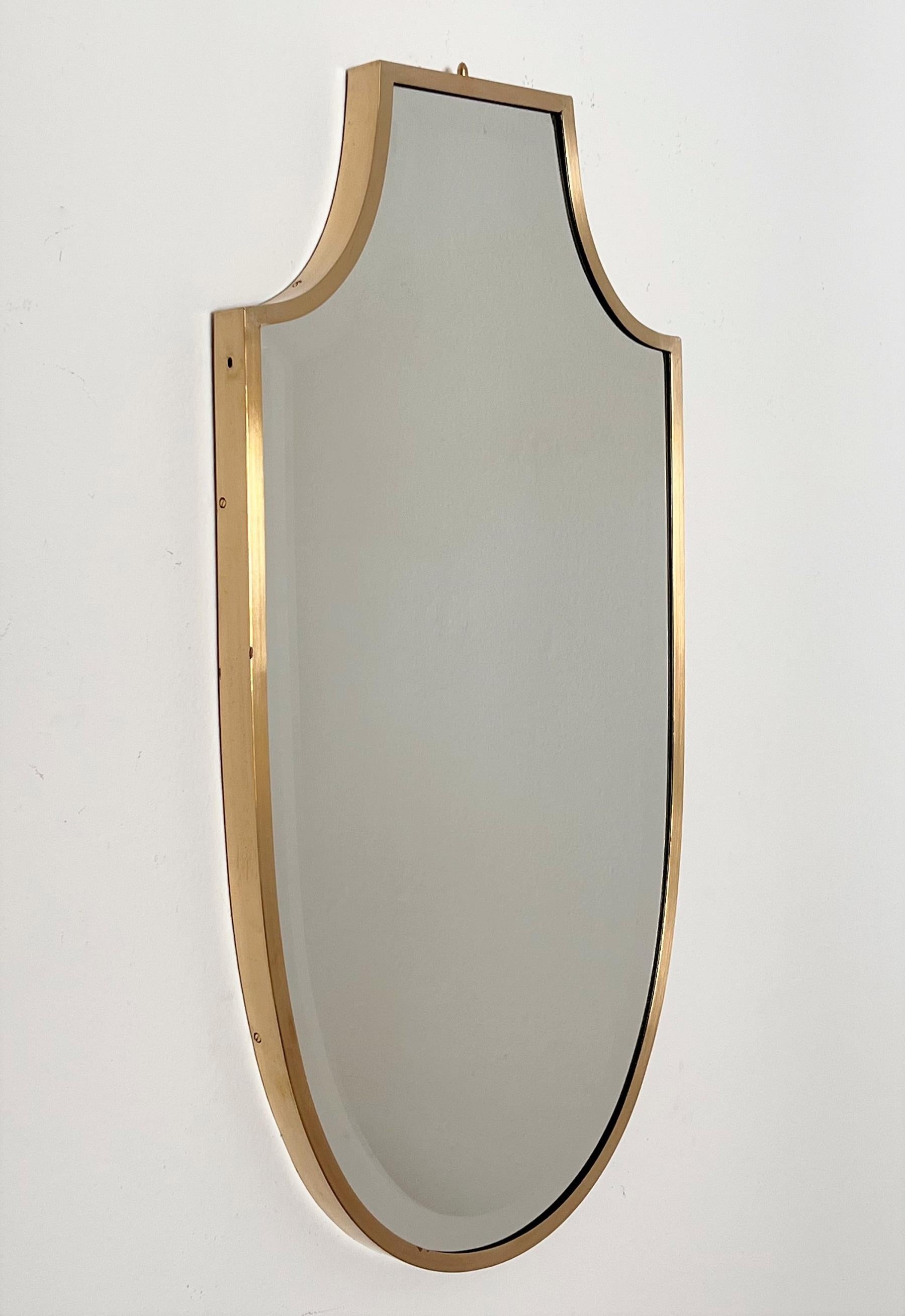 Magnifique miroir mural en forme de bouclier avec miroir en verre taillé d'excellente facture.
Fabriqué en Italie à la fin des années 1970.
Le cadre plein et épais en laiton a été nettoyé professionnellement, le verre miroir avec bordure en verre