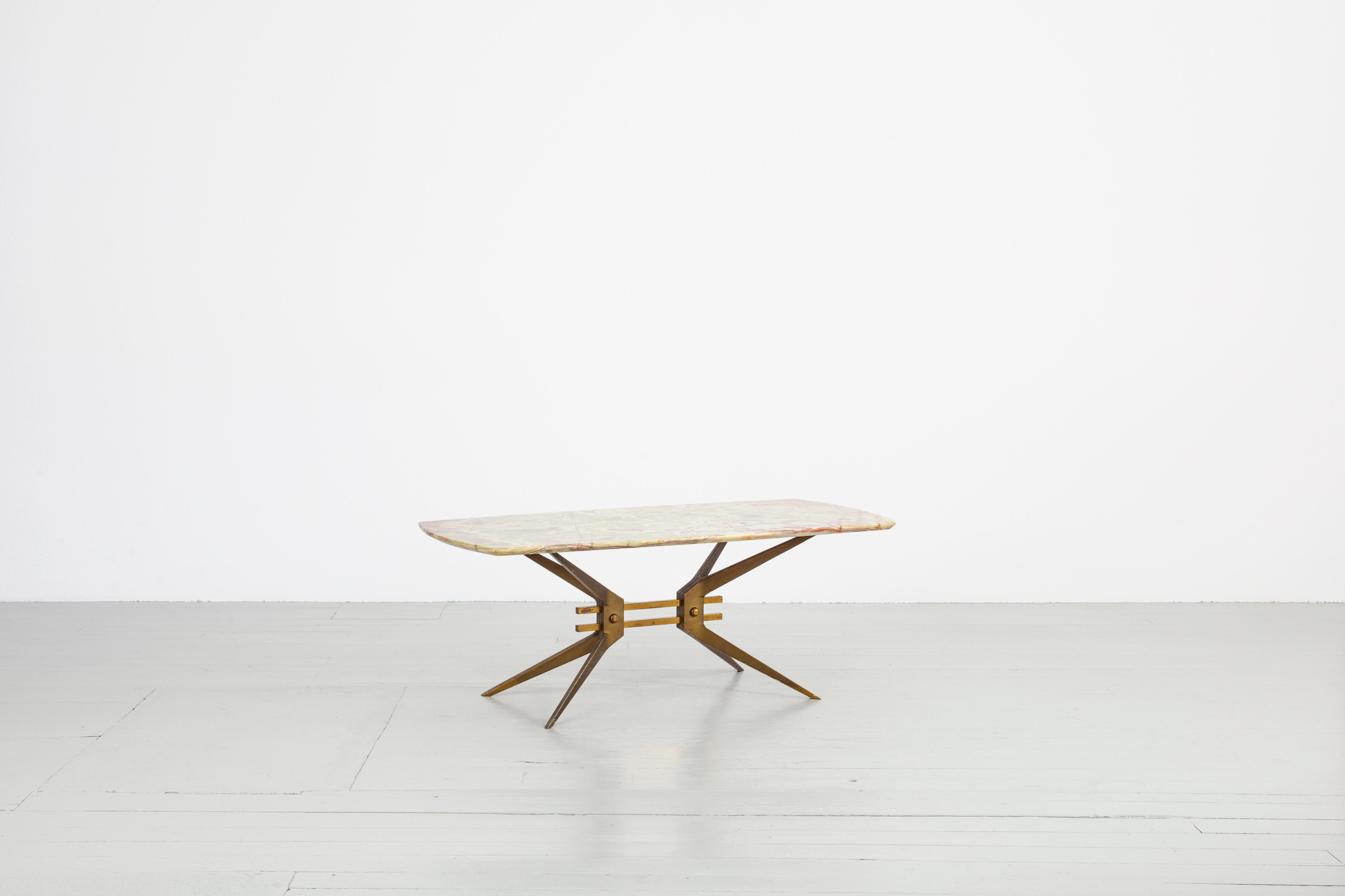 Cette table basse robuste a été fabriquée en Italie dans les années 1960. Le cadre de la table est une base stable pour le lourd plateau en Onyx. Deux entretoises en laiton relient les pieds effilés de la table pour former un cadre en X. La