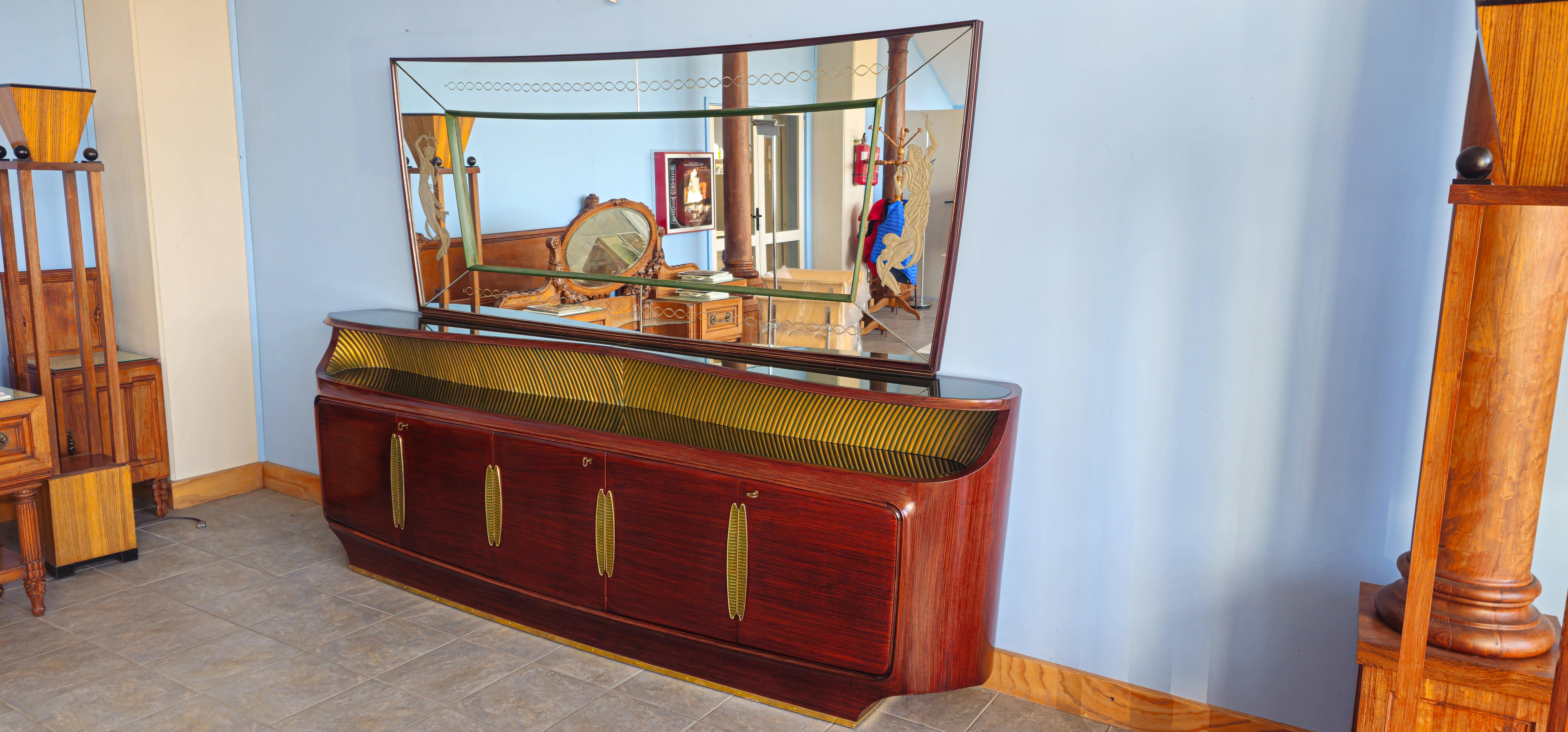 Questo mobile, con la sua combinazione unica di legni pregiati, curve scultoree e l'uso distintivo dell'ottone e dello specchio acidato, una forma di artigianato celebrata dal design italiano negli anni '40, è un'opera d'arte. In Europa, lo stile