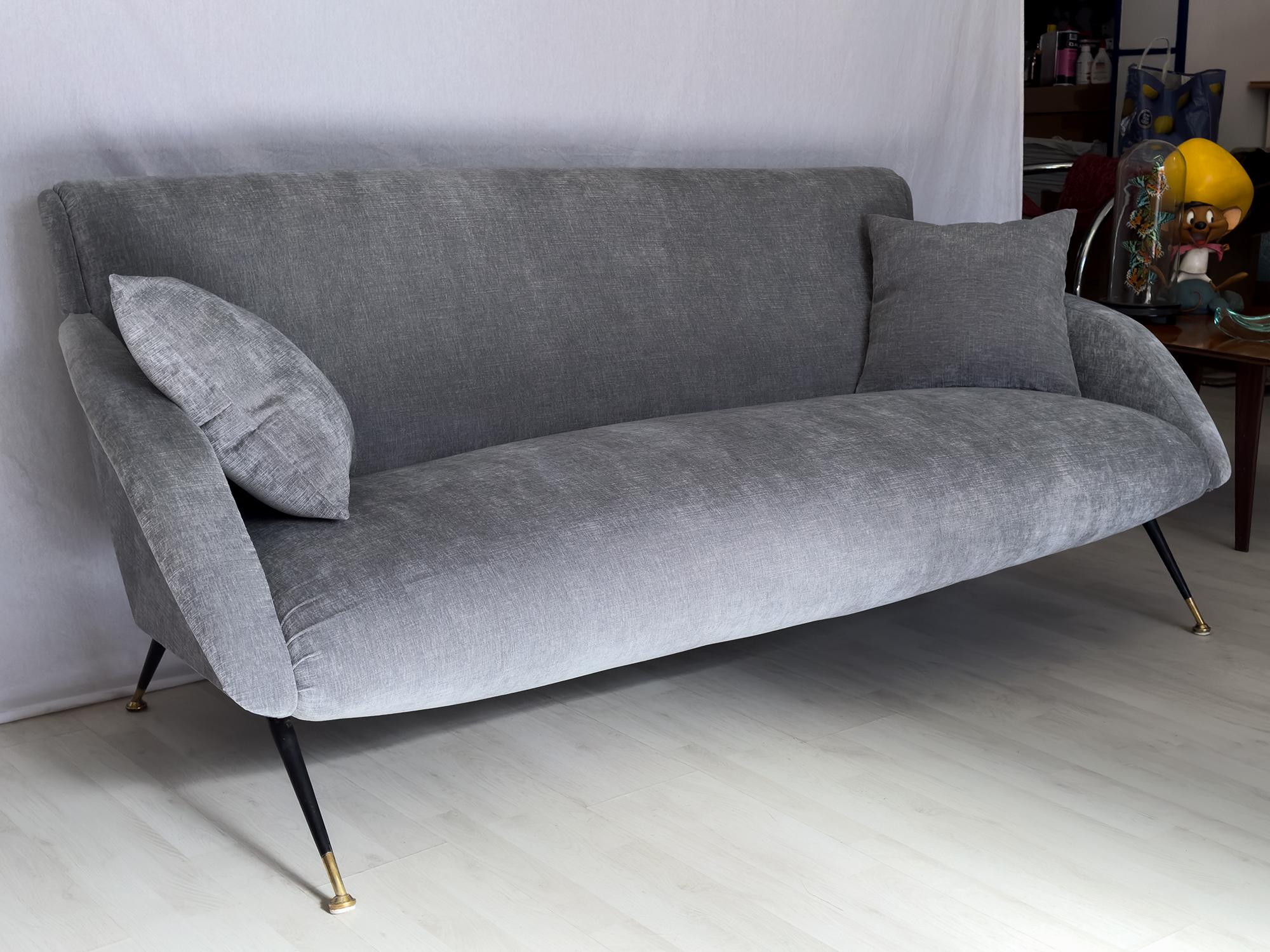 Stunning Italian midcentury three-seater sofa, with deep and very comfortable seating to provide a relaxing session.
The structure is very sturdy, supported by tapered black iron legs with brass feet, and it has been completely reupholstered with a
