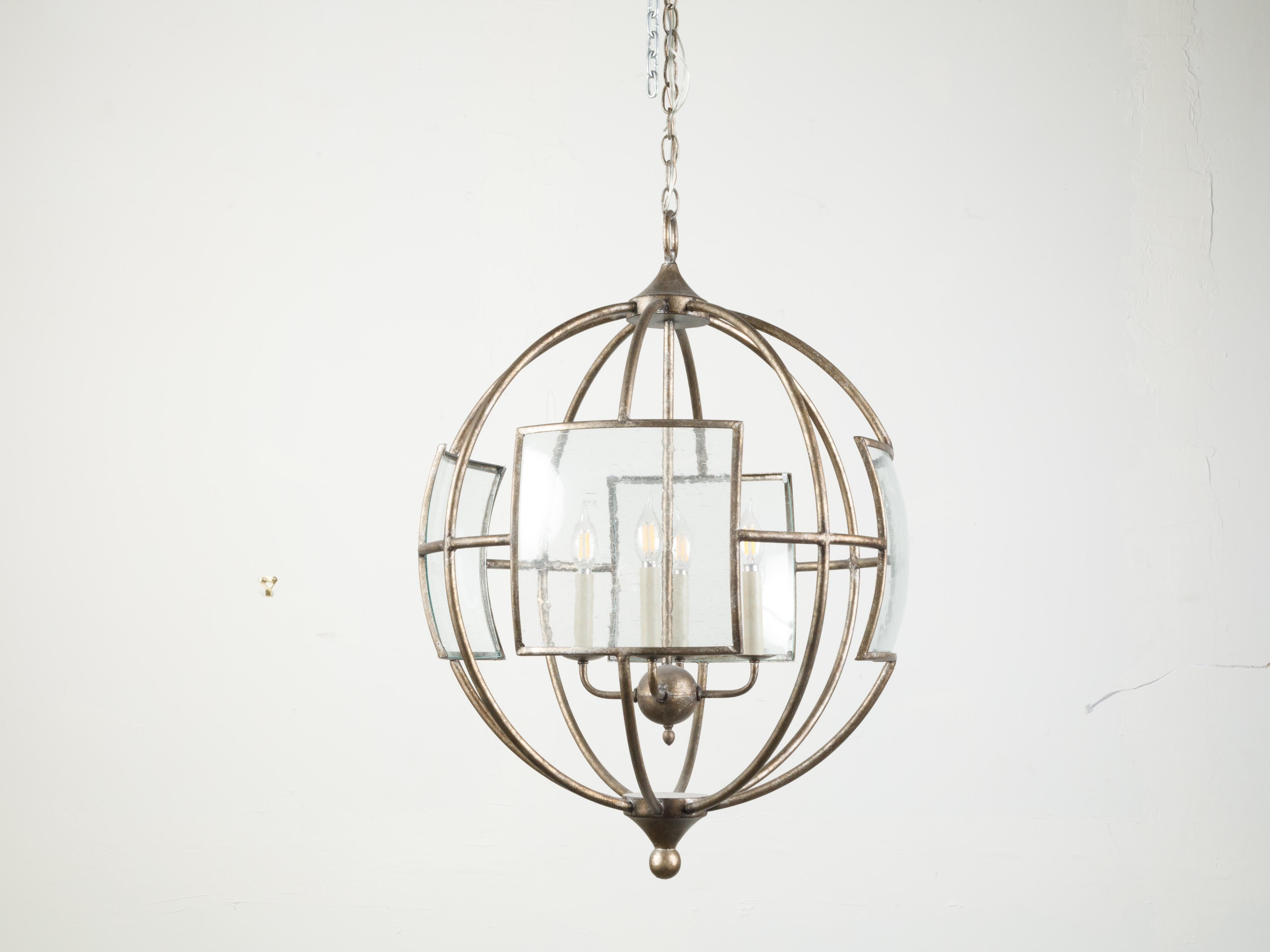 An Italian vintage spherical iron chandelier from the mid 20th century, with four lights and glass panels. Created in Italy during the midcentury period, this iron chandelier captures our attention with its spherical iron structure accented with