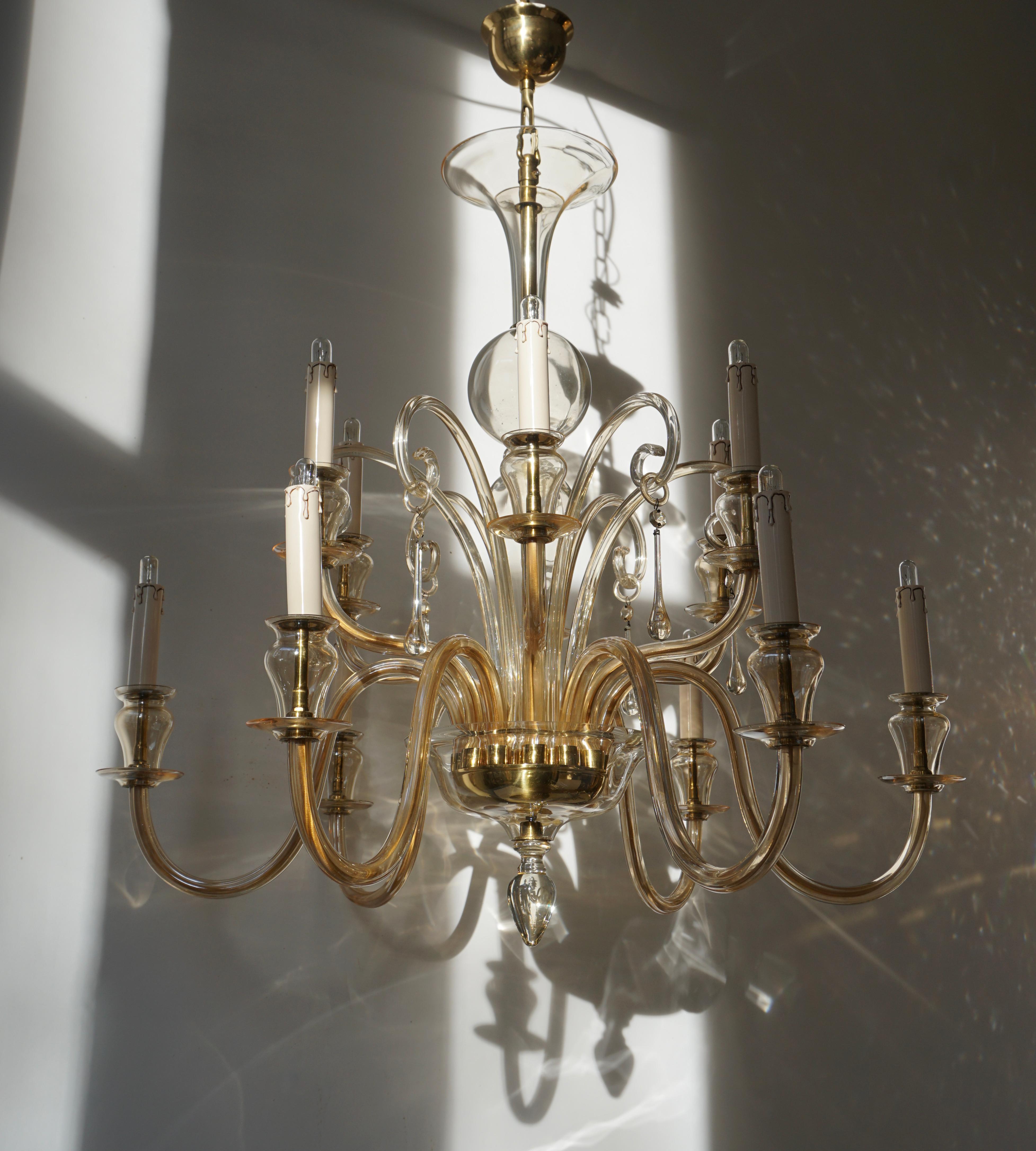 1970s Murano glass chandelier.

Contemporary Italian midcentury style, clear hand blown Venetian glass chandeliers or pendants in the modern neoclassical style with twelve arms attributed to Barovier with brass trim. Beautiful and fully working