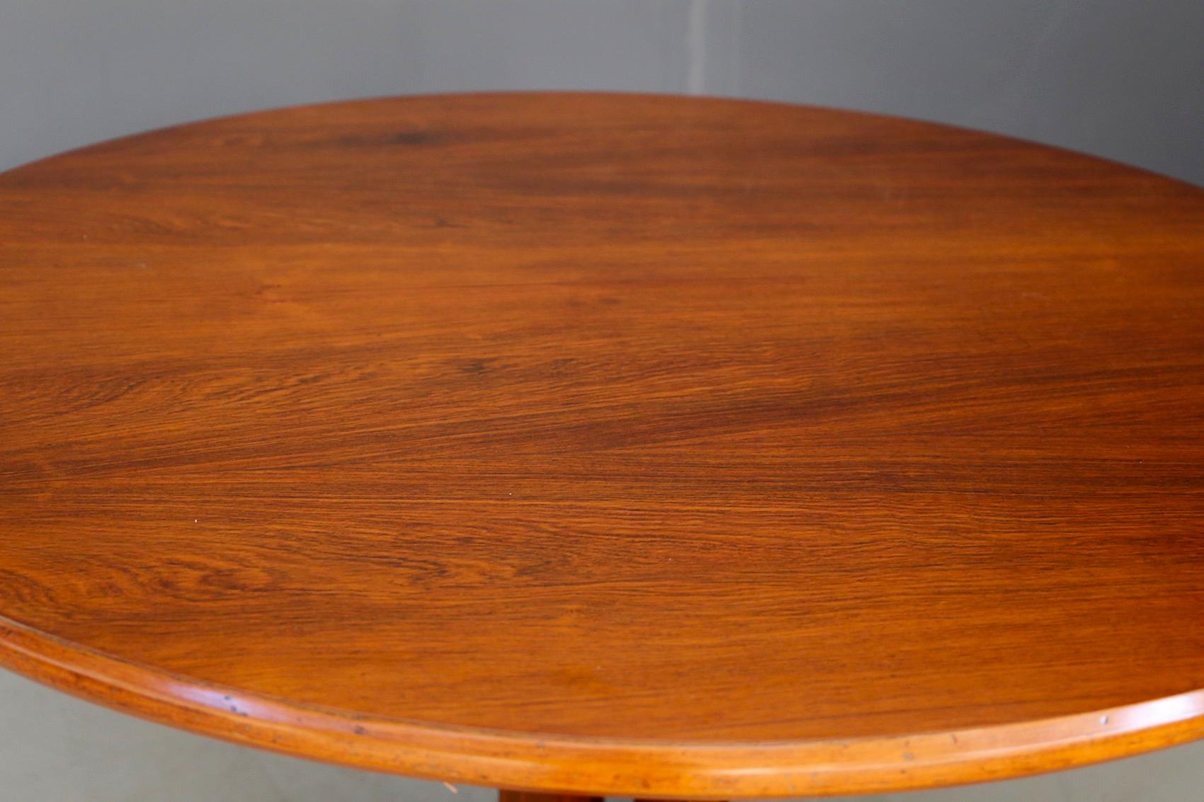 Elegant round dining table of midcentury Italian manufacture attributed to Gianfranco Frattini. The table has a circular mahogany wood top. The peculiarity of the table is its pedestal made of recessed wooden rectangles. As a base we find 4 wooden