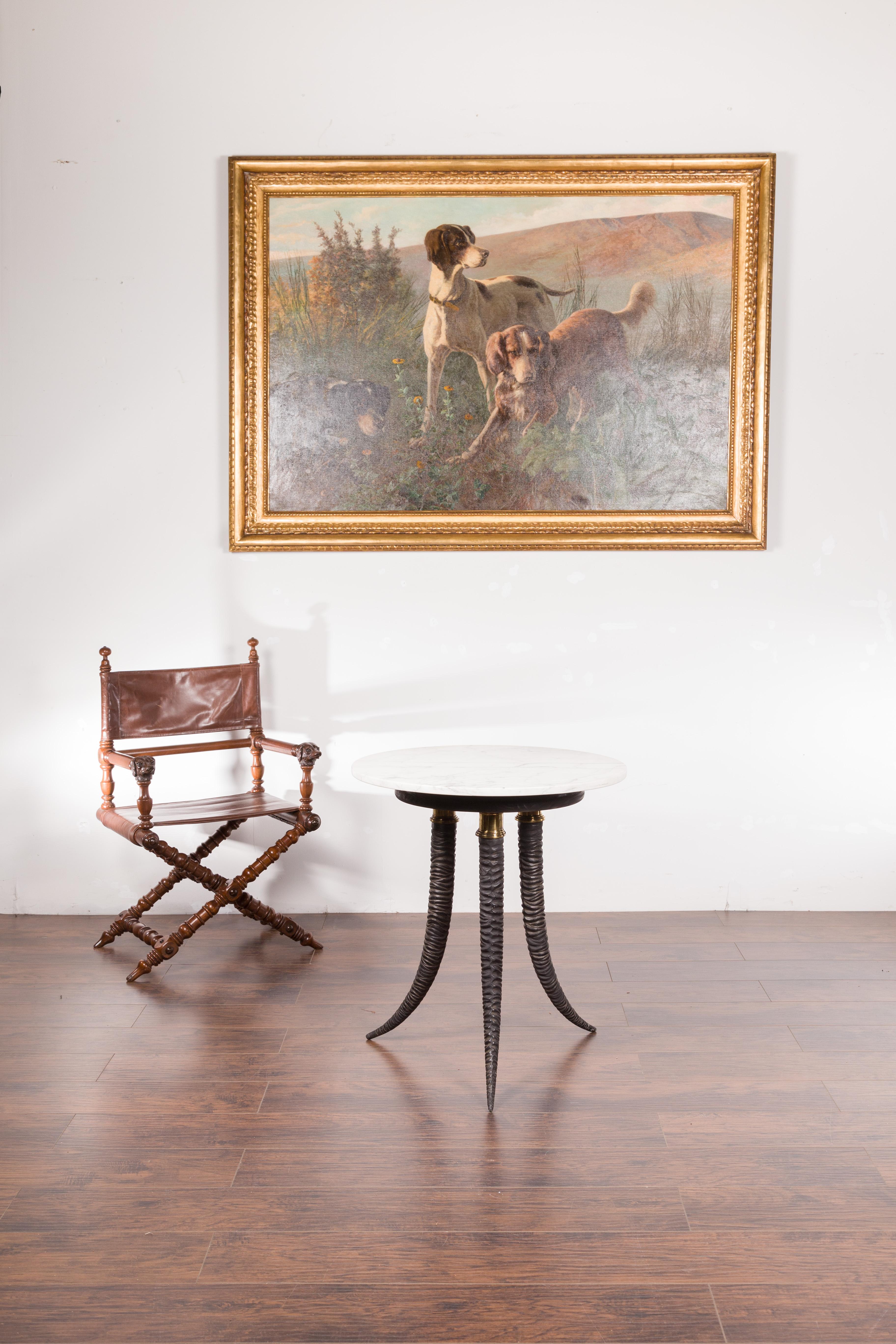 An Italian metal side table from the mid-20th century, with horn style base and white marble top. Created in Italy during the midcentury period, this side table immediately attracts our attention with its tripod Horn style base, supporting a