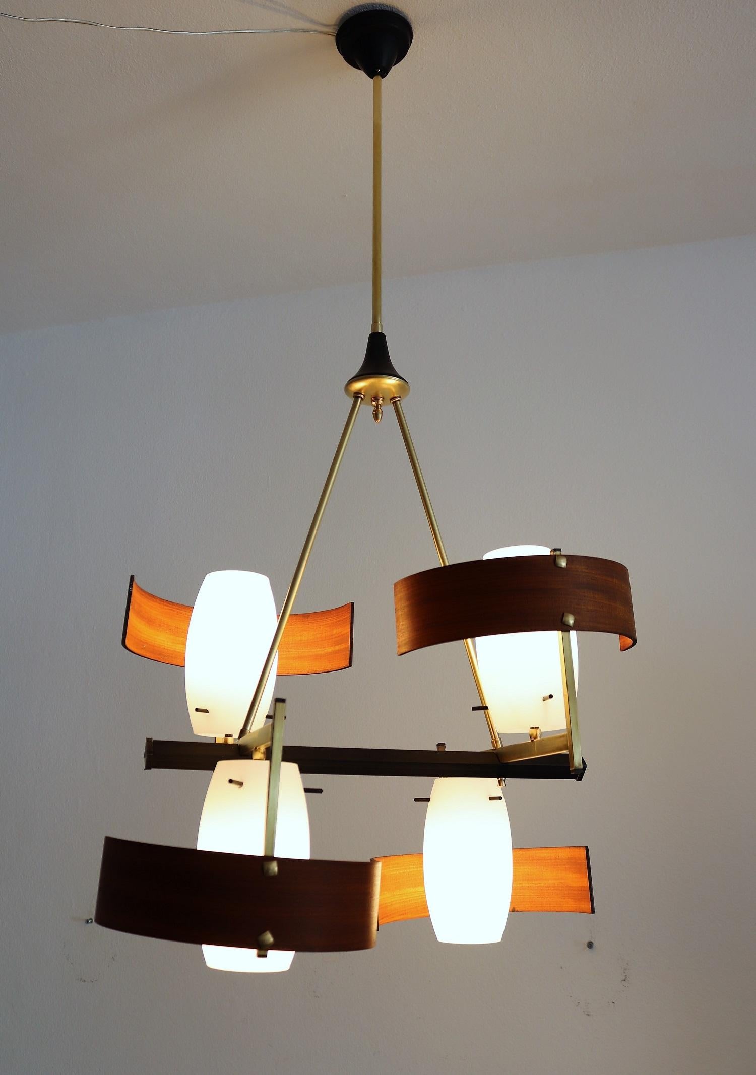 Beautiful Italian modernist chandelier made of teak and 4 white glass shades with brass and metal lamp frame and many brass details.
Typically for the modernist era of the 1960s.
All brass and metal details have been polished, the teak wood is in