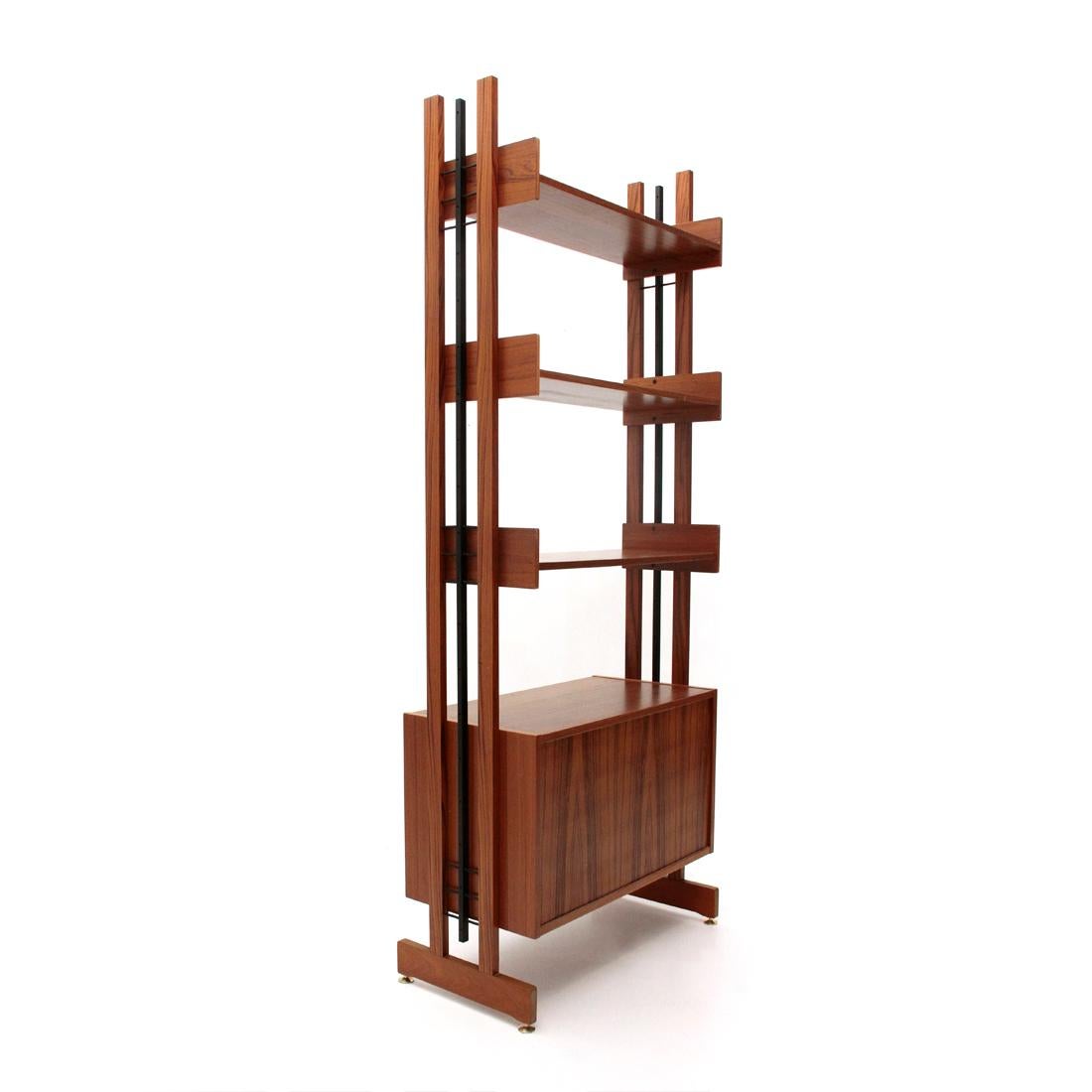 Italian manufacture wall unit produced in the 1960s.
Uprights in teak and black painted metal, height adjustable brass feet.
Teak veneered wood container and handles in black painted metal, inside shelf.
Shelves in teak veneered wood and plywood