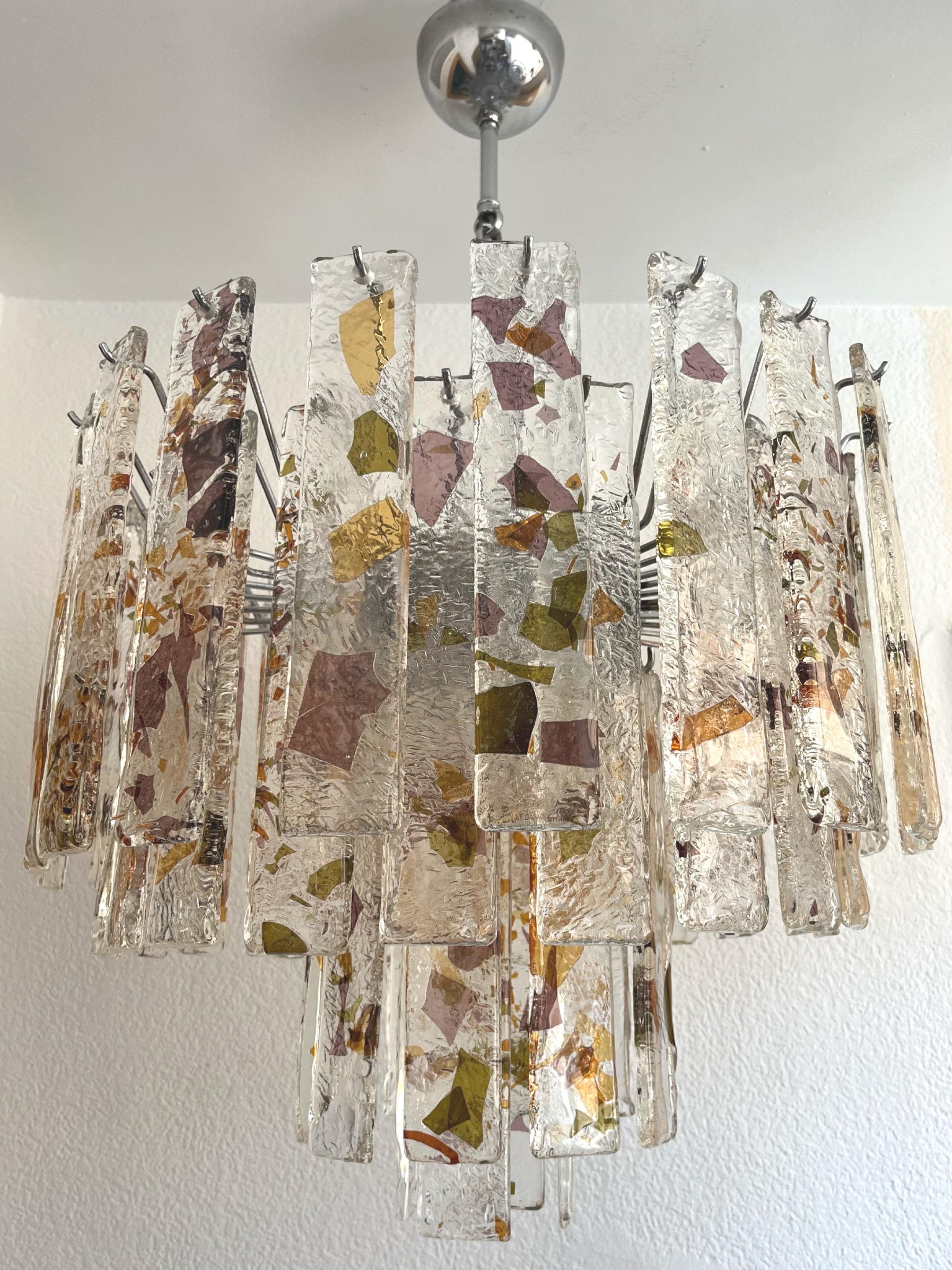 Unique, marvelous and large Italian lilac Murano glass Midcentury chandelier. This chandelier was made during the 1970s in Italy.
The Murano glasses are in clear color with fragments of papers in lilac, green and amber, embedded inside the