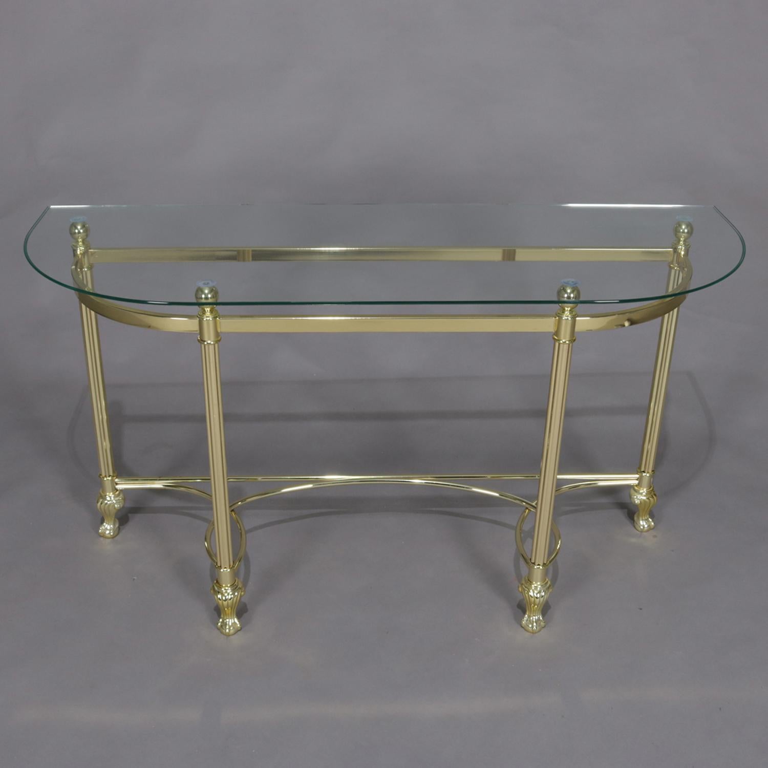 Italian transitional console table features demilune form with glass top over brass frame having open single rail apron with four reeded legs terminating in paw feet with scrolled stretcher, circa 1970.

Measures: 27.5