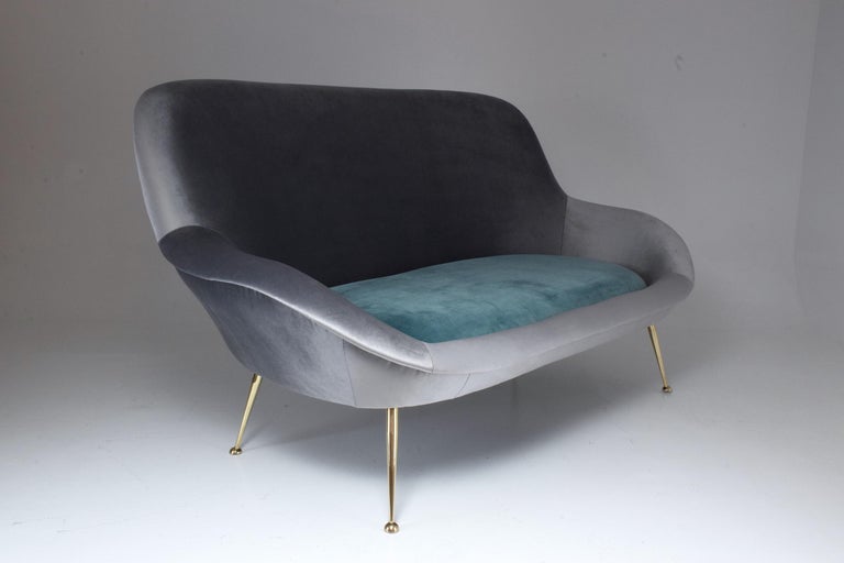 A rare 20th-century Italian sofa manufactured by ISA Bergamo and designed in an organic curved shape with a cushioned outer ring and comfortable depth which sits on splayed polished brass legs.
In fully restored condition and re-upholstered in a