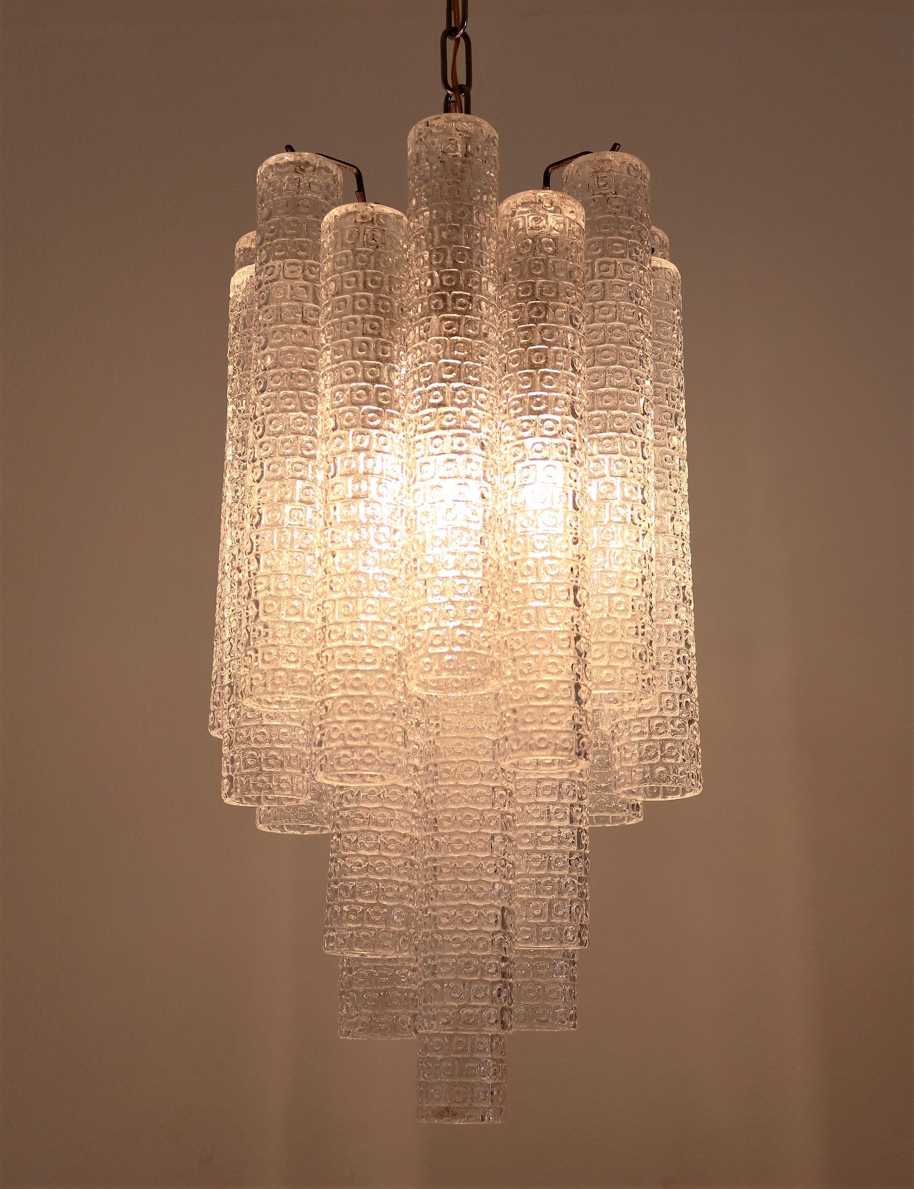 A gorgeous original vintage modernistic chandelier, produced circa 1960s-1970s in Italy by Venini.
Surrounded by 21 pcs. Staggered textured glass tube prisms on curvy hooks, typical for Venini, suspended from a chrome frame.
Requires 3 standard