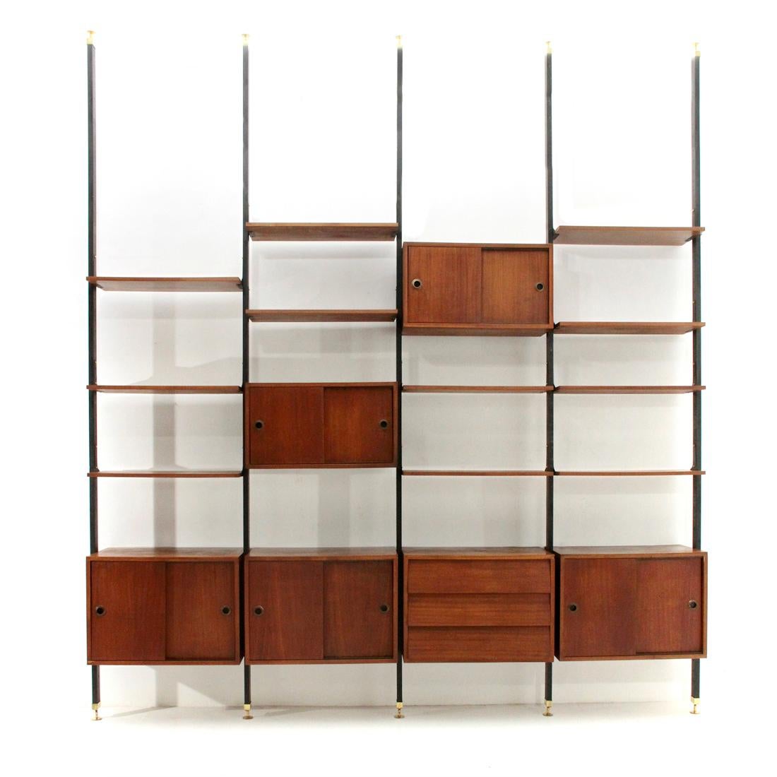 Italian manufacture wall unit produced in the 1960s.
Uprights in black painted metal box, height-adjustable brass feet.
Storage compartments and shelves in honeycomb veneered teak.
Handles in black painted brass.
Drawers with burglary