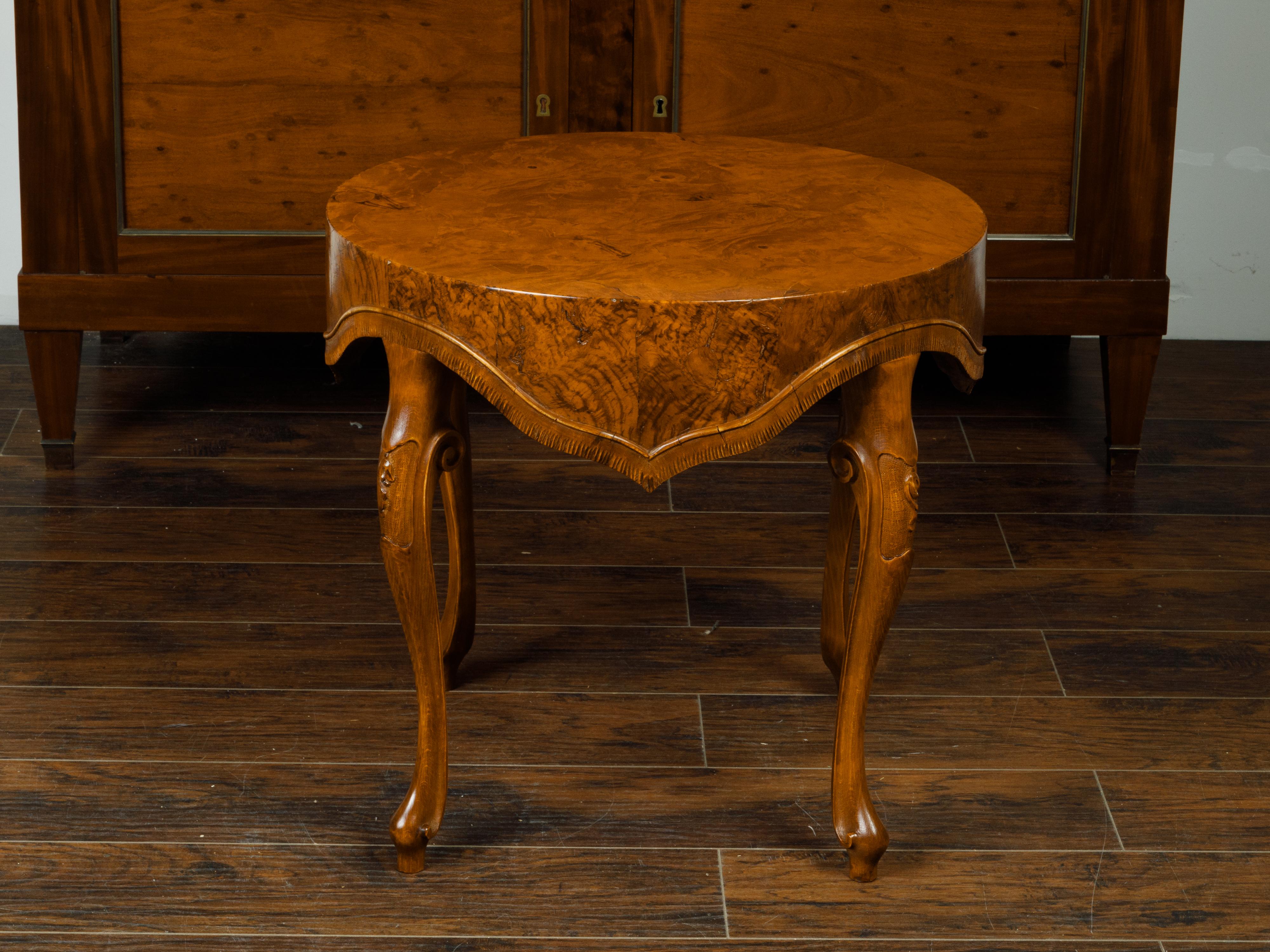 An Italian walnut side table from the mid 20th century, with round top, unusual carved apron and cabriole legs. Created in Italy during the midcentury period, this burl walnut side table features a circular top sitting above a handsome apron