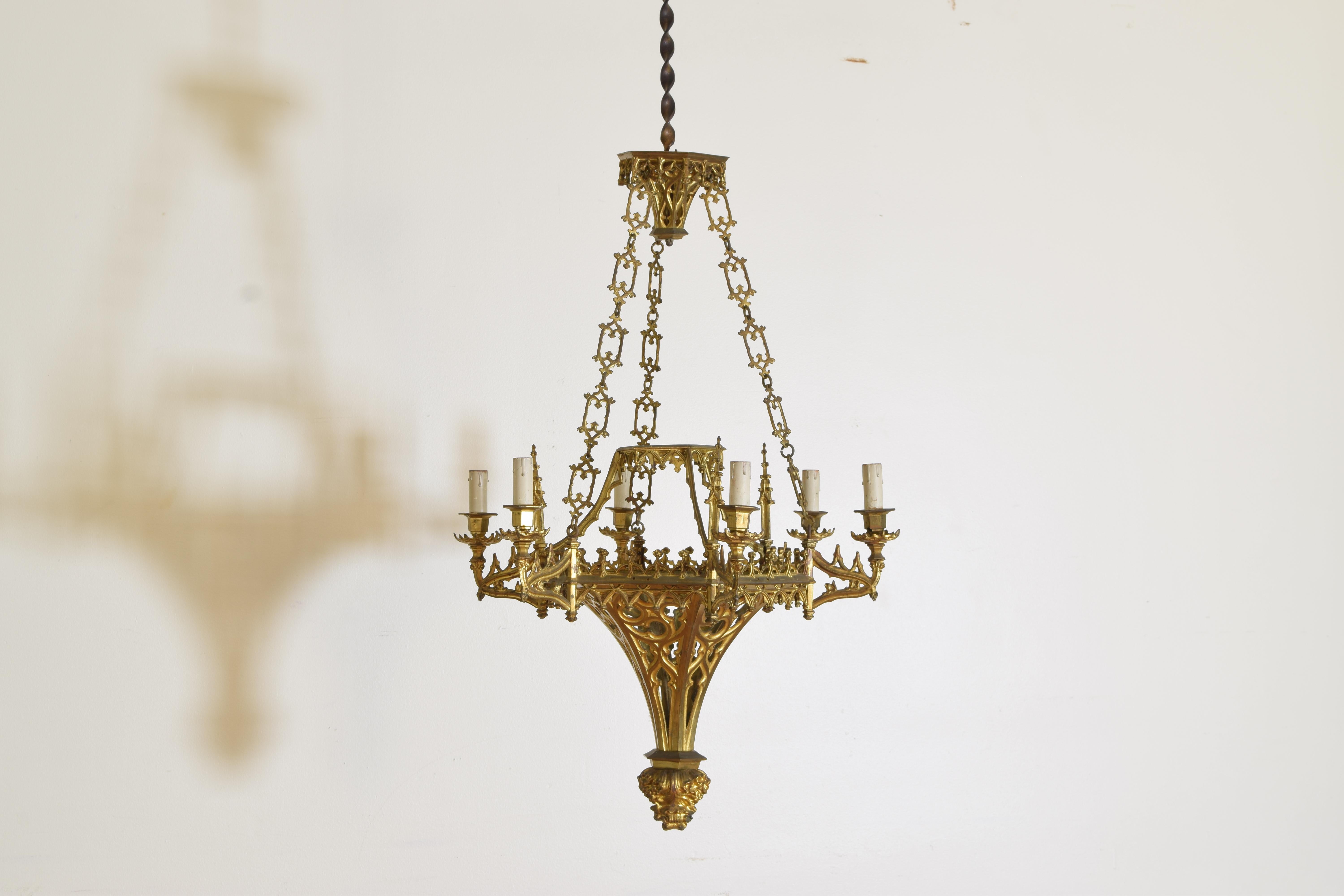 Of the gothic revival period, this circa 1865 chandelier hangs from an ornate canopy, the body constructed of gothic arches and spires and issuing six arms.