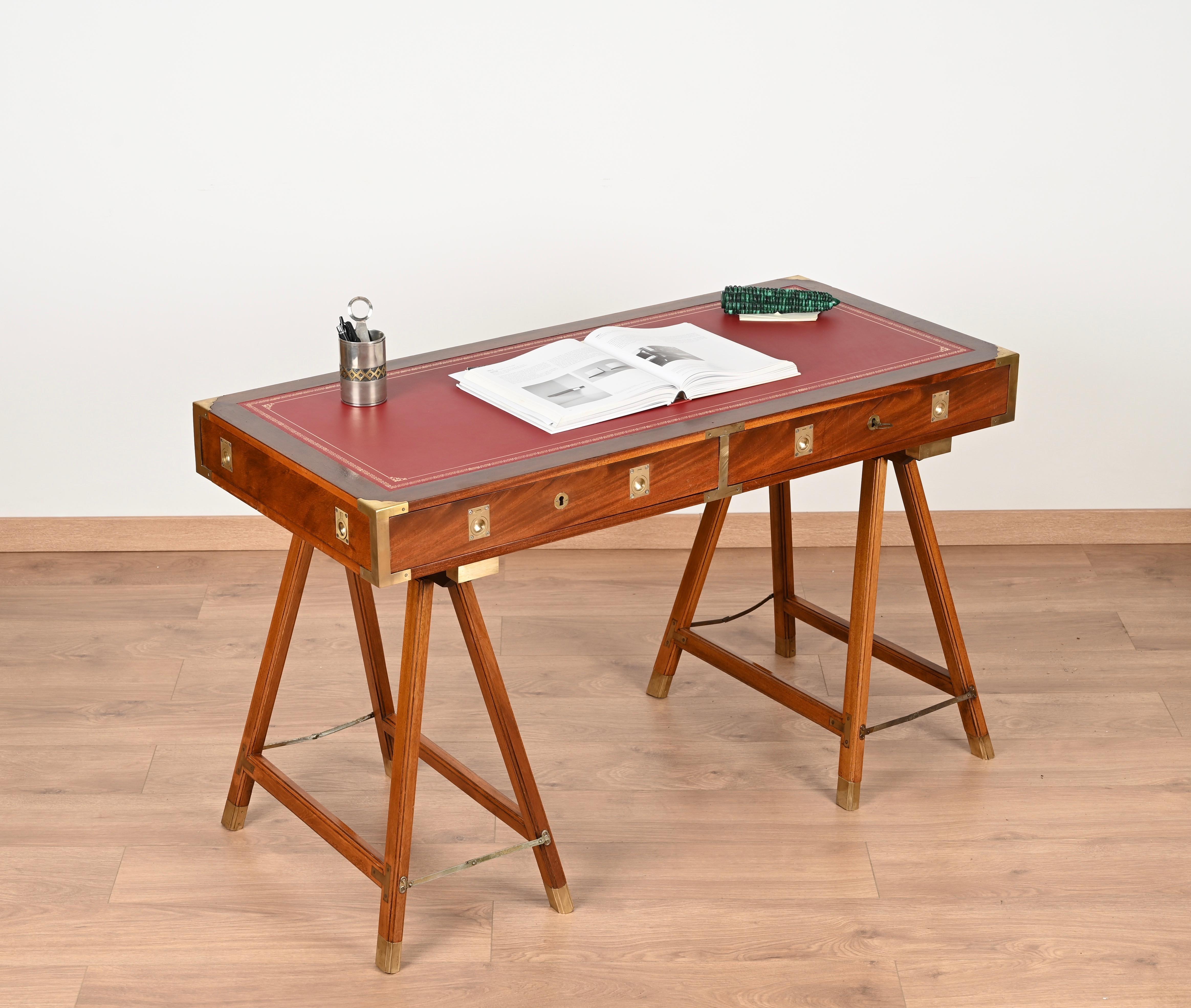 Stunning Mid-Century military campaign desk. This fantastic piece was made in Italy in the 1960s.

This trestle desk is made from a beautiful wood with exceptional grain, the top is decorated with a beautiful dark red leather which is enriched with