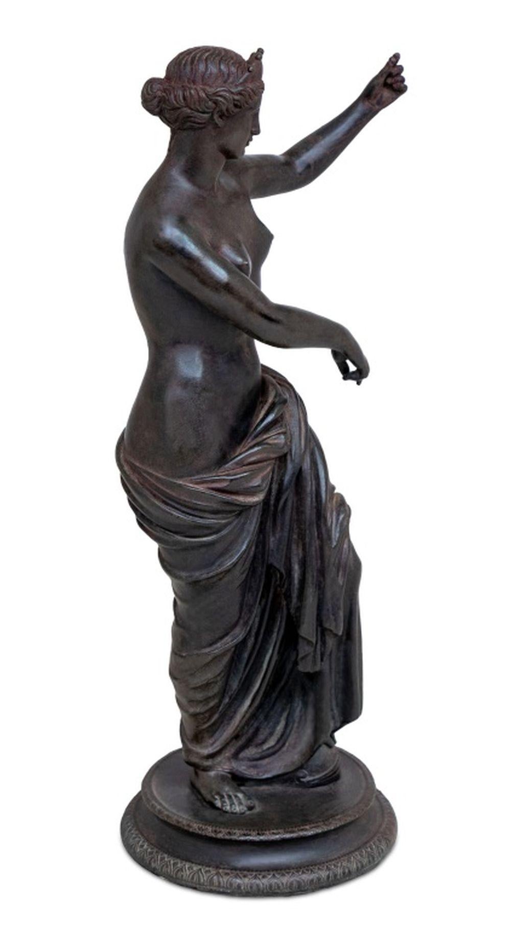 After the Antique Venus of Capua Patinated Bronze Sculpture, 19th century, possibly cast by Chiurazzi, the standing draped figure with outstretched arm, with a foot resting on a helmet, circular base. 17